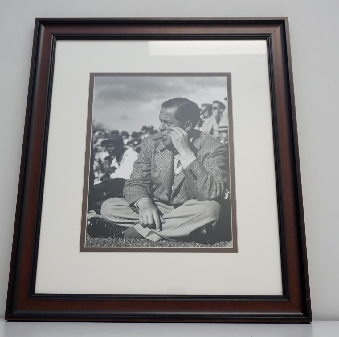 BOBBY JONES 1930S MASTERS PHOTO: Framed Photograph of Bobby Jones enjoys a cigar while watching players practice putting and chipping from a knoll above the putting green during a Masters Tournament at Augusta National Golf Club duri