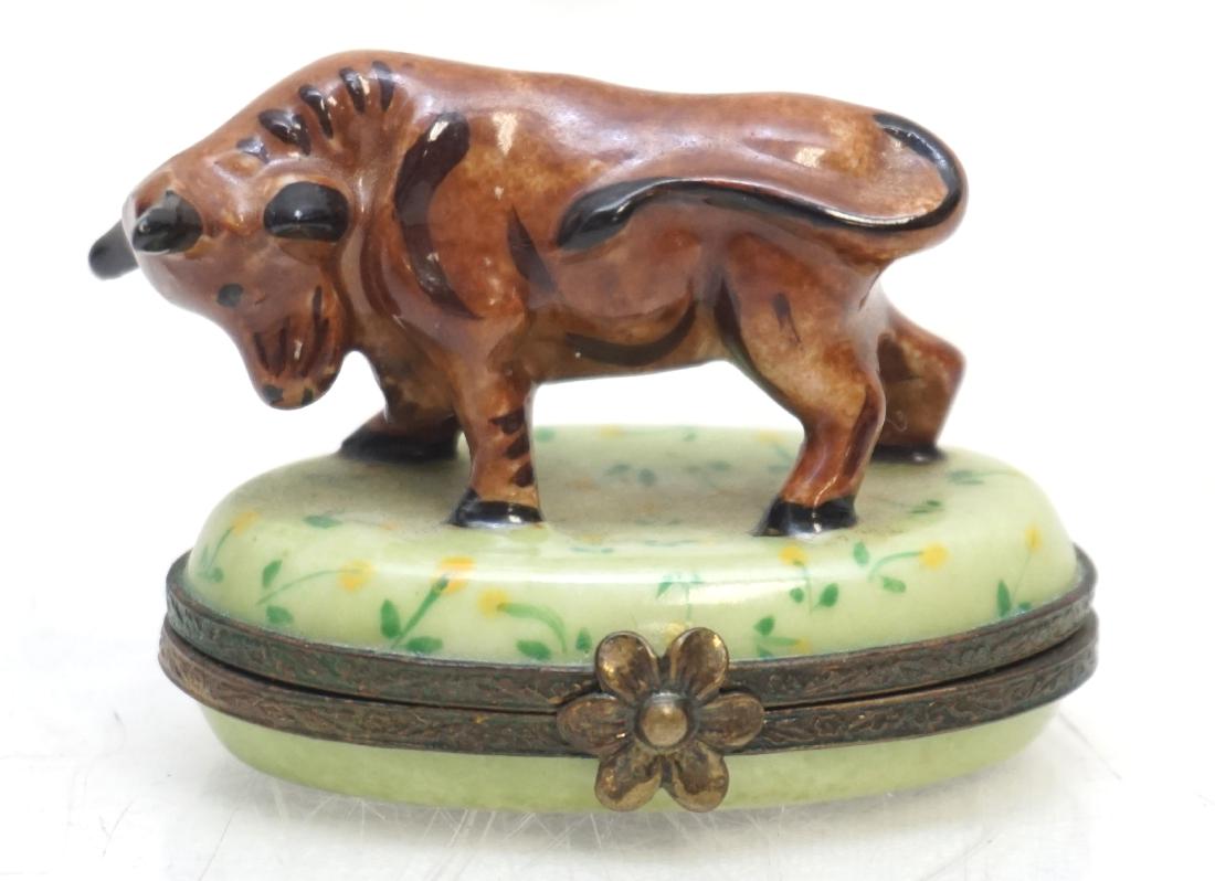 LIMOGES PEINT MAIN BULL BOX: Vintage Limoges Porcelain Peint Main Bull Trinket Box. Hand painted, floral clasp, opens to reveal a small flower hand painted inside. Measures 2"x1 1/2"x1 1/2". PROVENANCE: A Private Charleston SC Es