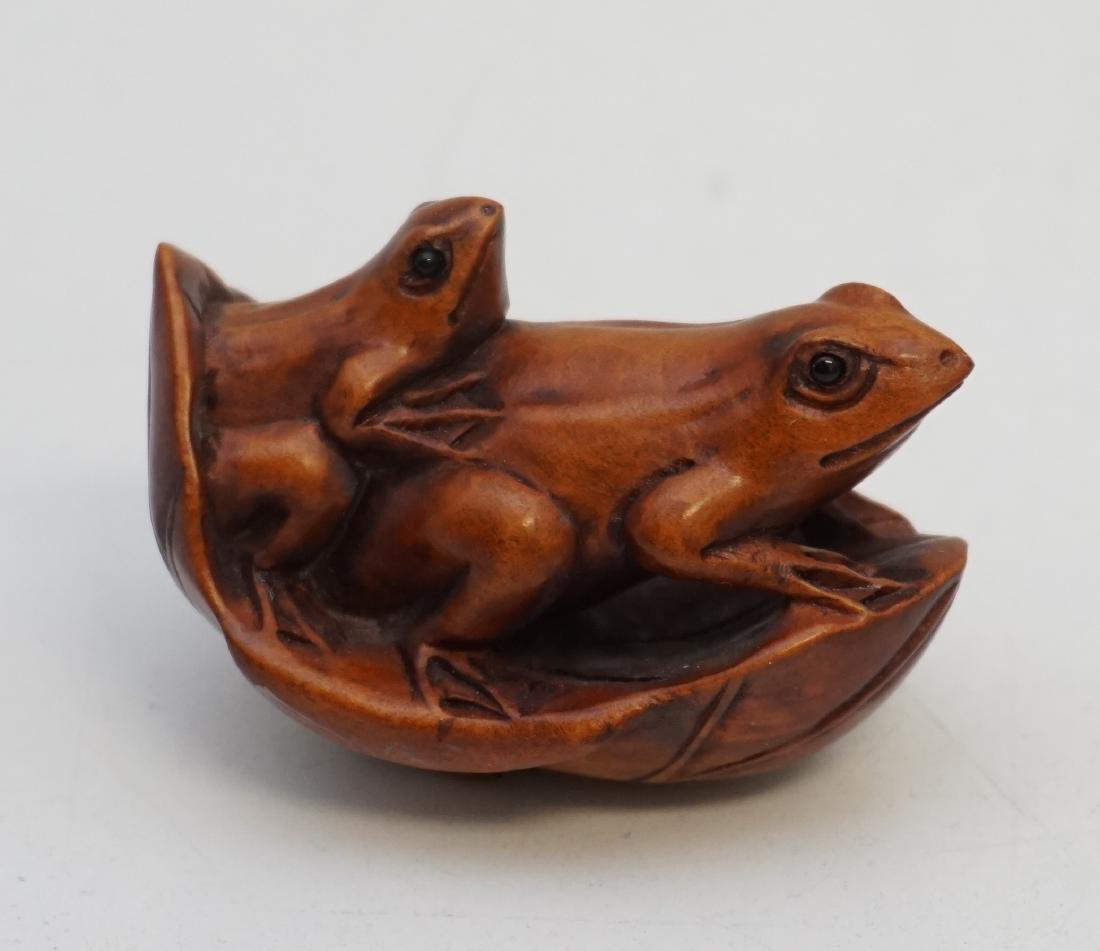 SIGNED CARVED BOXWOOD FROGS NETSUKE: Vintage well carved Japanese Boxwood Mother and Child Frogs on a Lily Pad. Signed by the artist c. 1960-70. Measures 2". PROVENANCE: A Charleston SC Private Estate.