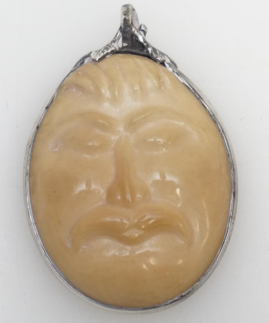INUIT HAND CARVED FACE PENDANT: Inuit Finely Hand Carved Alaskan Walrus Fossil Dimensional Face Pendant. Signed by the artist on the back. Set in sterling. Measures 2" long. Weight 20 grams. PROVENANCE: A Private Charleston SC Estat