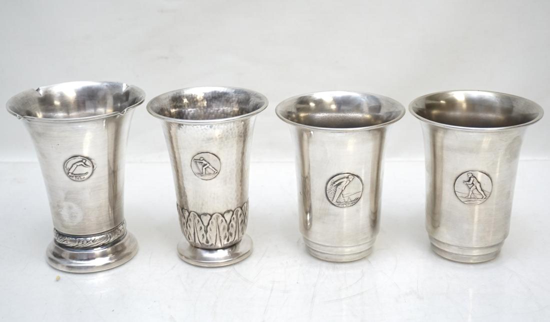 4 TROPHY / JULEP CUPS SKIING: Four Vintage Silver Plate and/or Nickel Silver Cross Country Skiing Trophy / Julep Cups. Various makers, all with skier medallions. All measure 4 1/2"to 4 1/2". Weight on all 15 oz. PROVENANCE: A Pawl