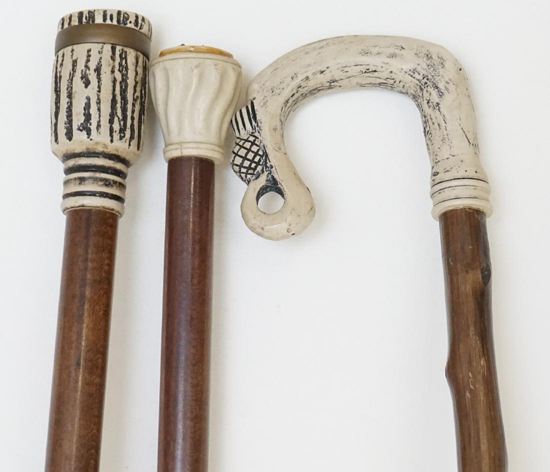 3 VINTAGE WALKING STICKS: Three composition faux antler walking stick / canes. 1 with compass top, 1 scrimshaw stag head, 1 with pineapple accent. All 32-34" long. Weight 2 ps 3 oz. PROVENANCE: A Charleston SC Private Estate.