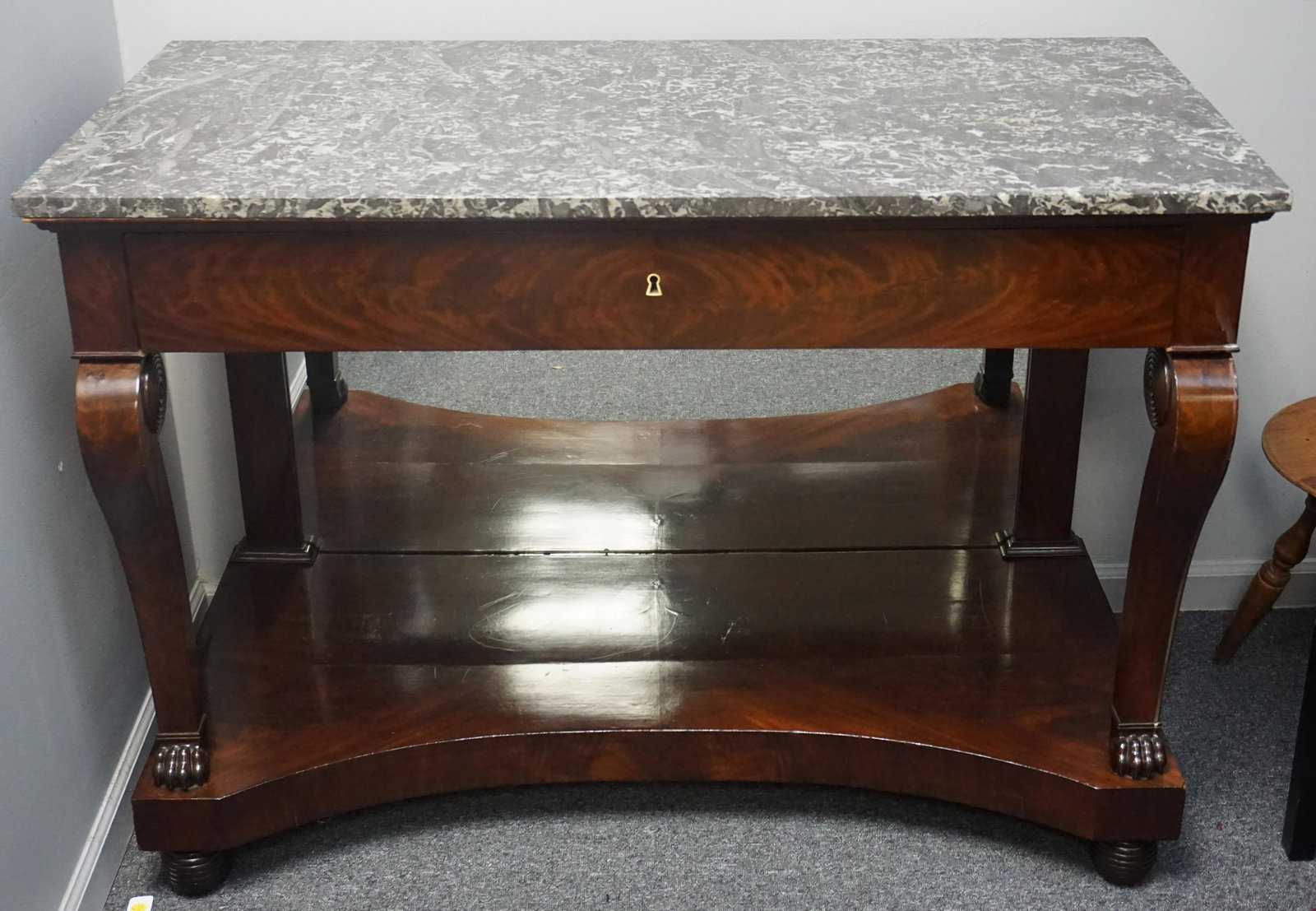 FRENCH CHARLES X CONSOLE TABLE: A very finely figured French Charles X period c. 1820 mahogany console table, one central drawer, mirrored back, supported upon two scrolling legs with paw feet, all terminating upon a block plinth wi