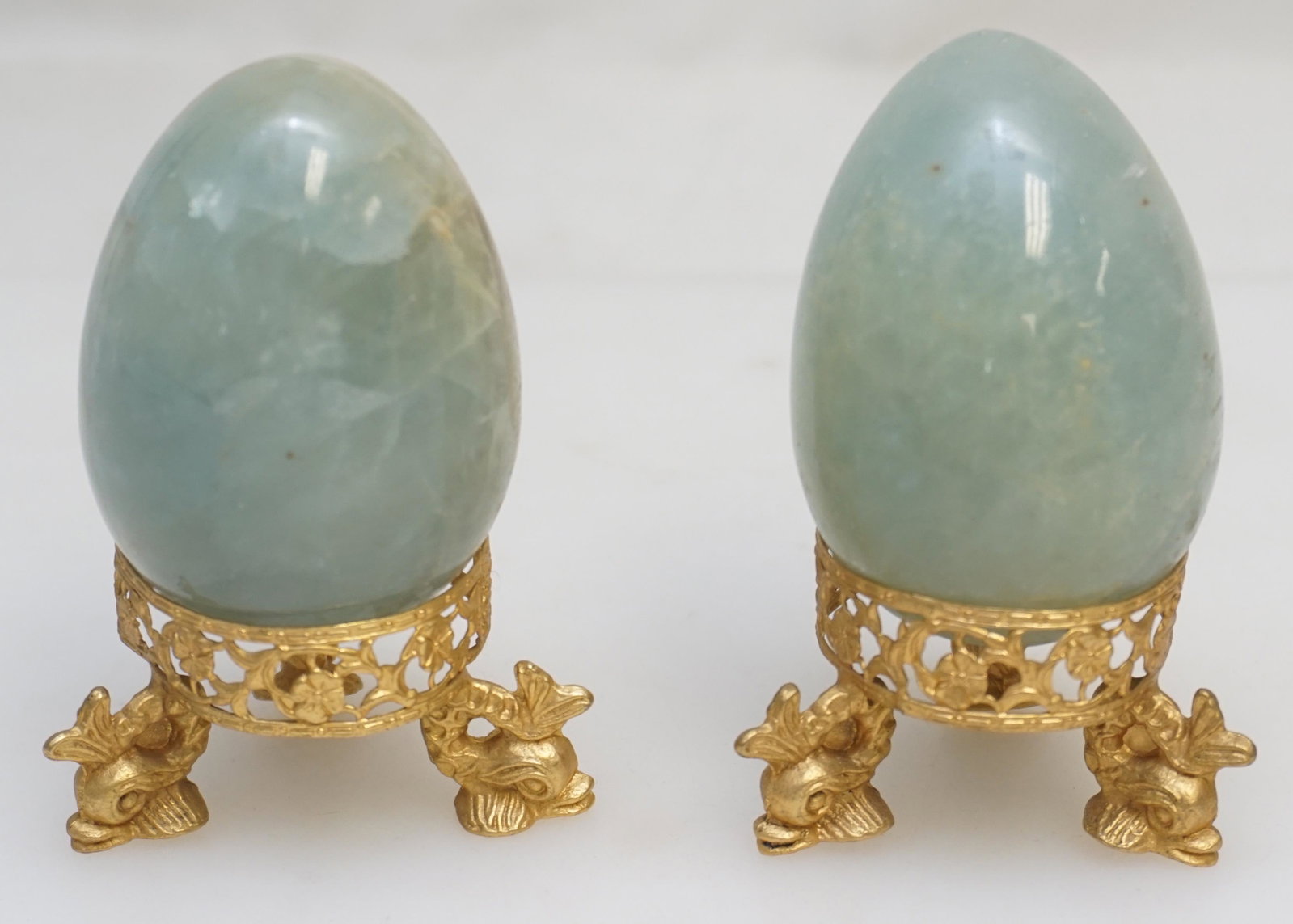 PAIR ONYX EGGS ON DOLPHIN STANDS: Pair of Carved and Polished Onyx Eggs on gilt dolphin stands. Each 3 3/4". Weight combined 1 pd 3 oz. PROVENANCE: A Private Charleston SC Estate