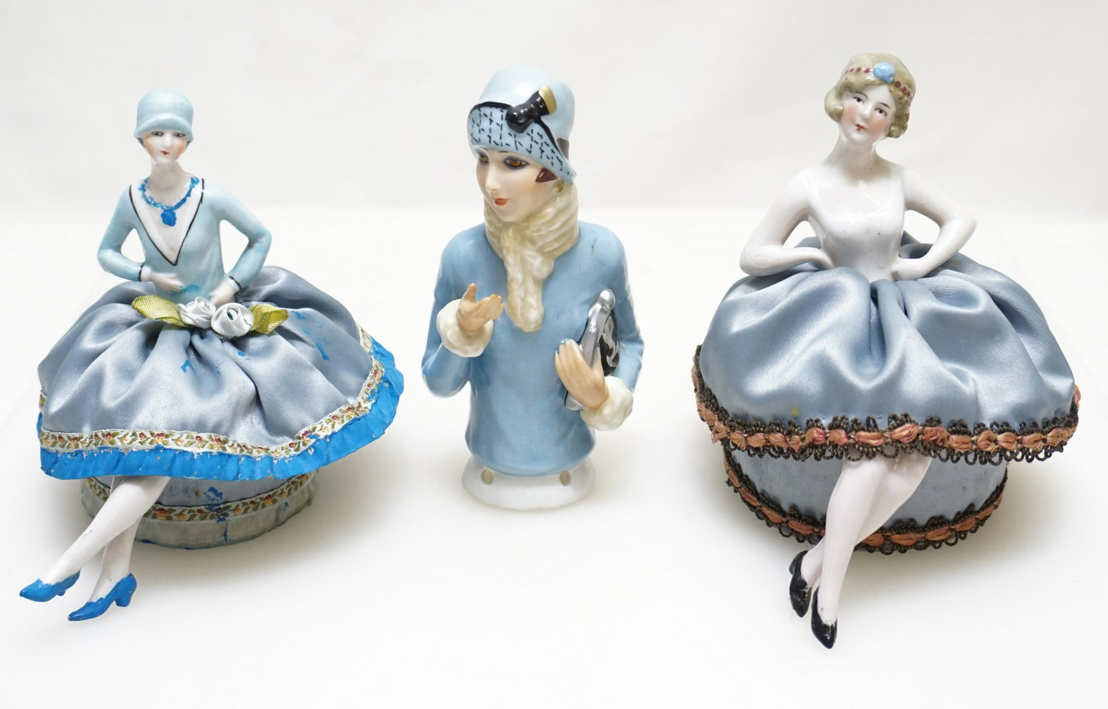 THREE VINTAGE PORCELAIN PINCUSHION DOLLS: Three Porcelain 1920s Flapper Pin Cushion Dolls. Two Complete and 1 half doll. Two seated approximately 4 1/2" , half doll 5". Good condition, 1 has blue paint on her skirt. Weight on all 12 oz. PROVE