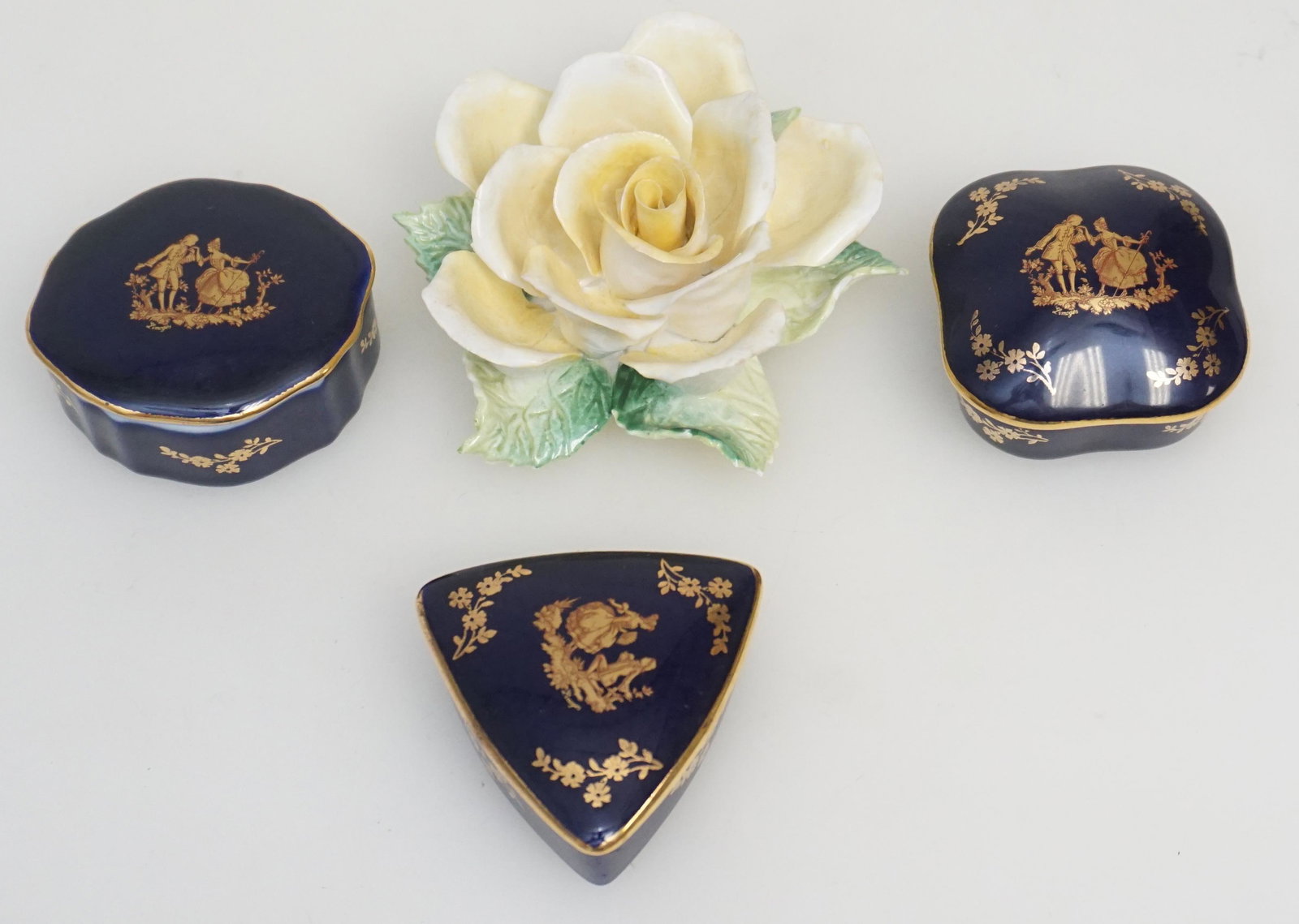 4 pc PORCELAIN LIMOGES + CROWN: 3 Vintage Limoges Cobalt and Gilt Trinket / Pill Boxes all approximately 2 1/4" long. Vintage Crown Bone China Yellow Rose, with 2 tiny nicks to leaves. 3 1/2". Weight on all 10 oz. PROVENANCE: A Priv