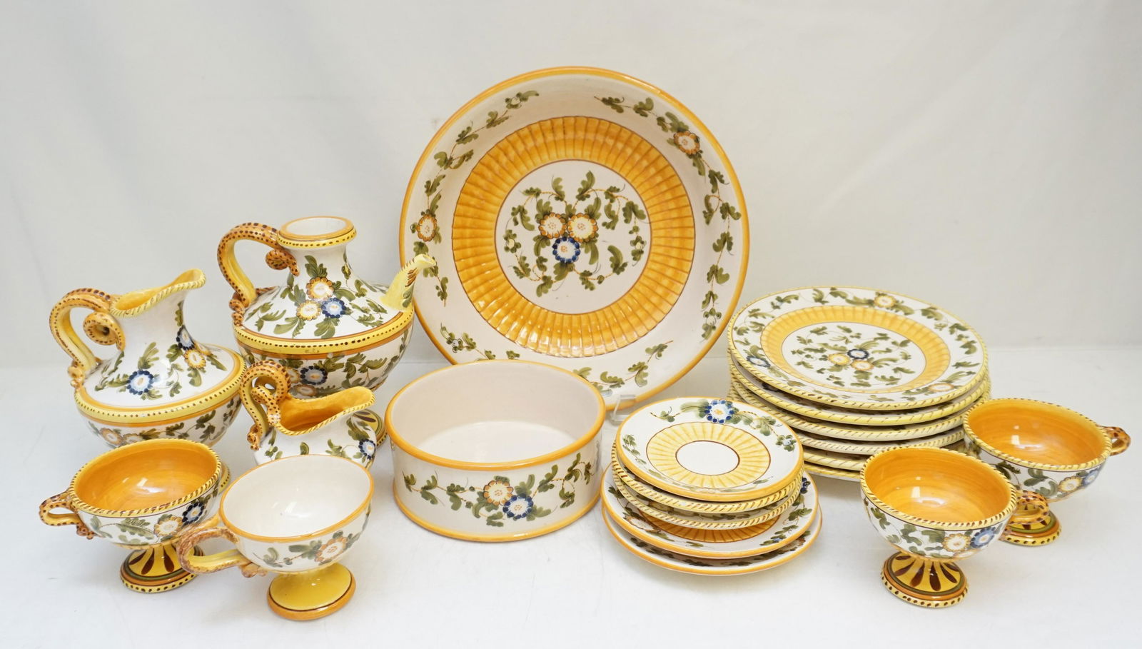 22 PC DERUTA ITALY HAND PAINTED POTTERY: 22 Piece Italian Hand Painted Deruta Pottery Items. Bowl 10 1/2"x10 1/2"x2 1/2". 6 Cake Plates 7 1/4". 4 Footed Cups with Snake Handles 2 3/4", 1 with crack to handle, 1 with thin hairline. 5 Saucers.