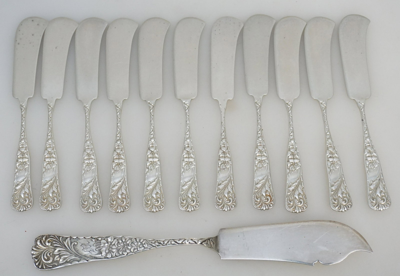 12 AMERICAN STERLING ORNATE BUTTER SPREADERS +: Eleven American Aesthetic Antique Sterling Silver Ornate Feather Plume and Lily Butter Spreaders and 1 Cheese Knife. Retailed at James McCaffrey Jewelers in Philadelphia. Ornate Repousse. Only Cheese