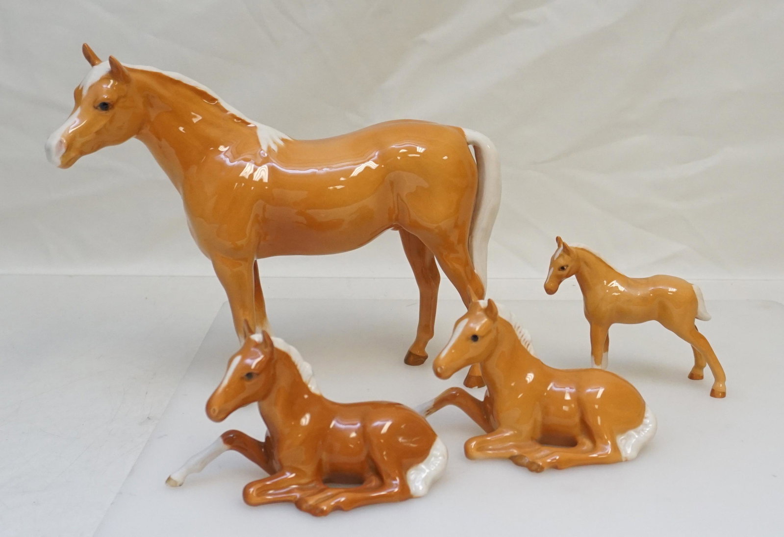 4 BESWICK PALOMINO HORSES: 3 Beswick and 1 Royal Doulton England Palomino Horses. Good Condition. Large 9" long and 7 14" tall. 2 Reclining Colts 915 each 5" long. Standing Royal Doulton 3"x3 1/4". Weight 1 pd 6 oz. PROVENANCE: