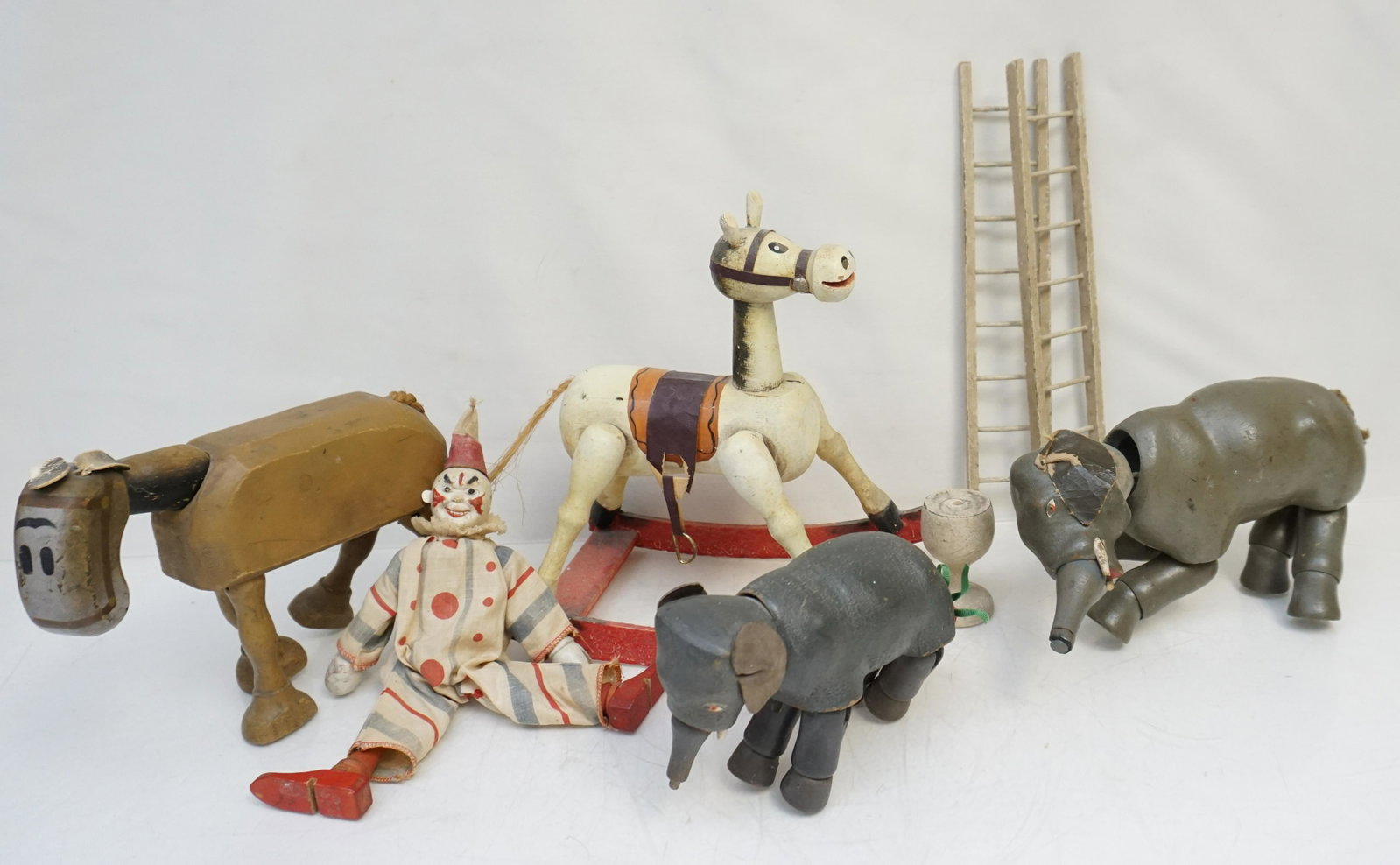 5 EARLY SCHOENHUT CIRCUS +: Five Early Schoenhut Wood Toys. Some from the Humpty Dumpty Circus. Elephant 7", Baby Elephant 4 1/2". Spark Plug 8". Clown with 2 ladders. Rocking Horse, back piece of rocker missing 10". Weight on a