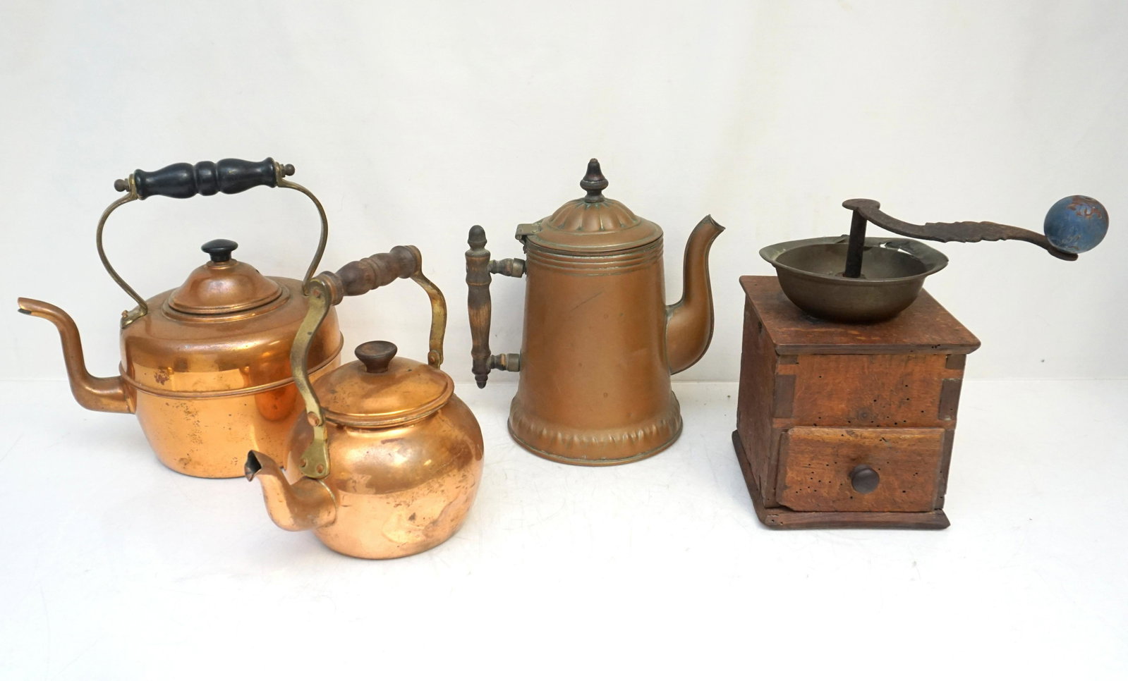 3 VINTAGE COPPER TEAPOTS + COFFEE GRINDER: 3 Vintage Copper Tea Pots and 1 Antique Wood Coffee Grinder. Tallest pot 9". All have dents. Weight on all