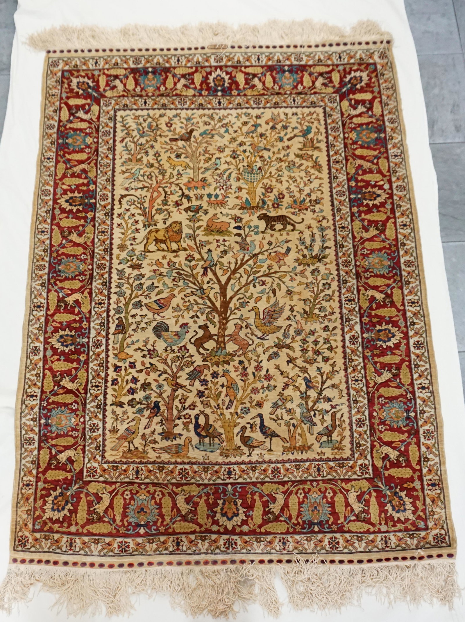 SIGNED FINE SILK NASR TREE OF LIFE RUG: 20th c. Super Fine Silk Ground 'Nasr' Rug (Tree Of Life) 'Signed'. Featuring an ivory ground and red borders. Excellent condition with Small Tear edge one side. Area Rug 5' X 3 1/2'. Measures 60"x41".