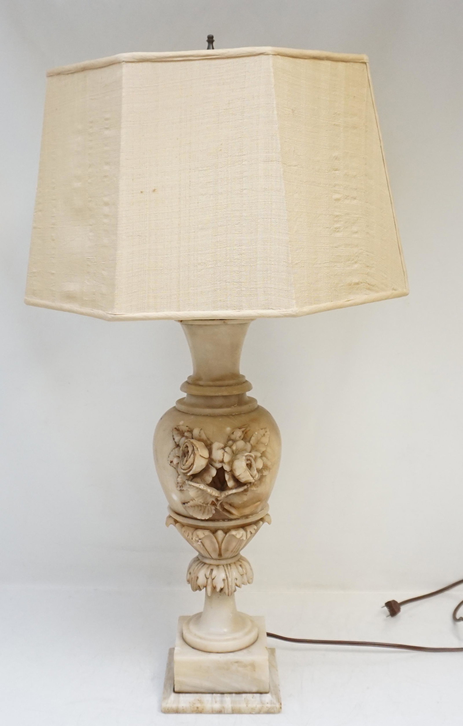 ANTIQUE ITALIAN ALABASTER RELIEF LAMP: Antique Hand Carved Relief Italian Alabaster Lamp. Having a design of carved flowers and acanthus leaves. Measures 5"x5"x27". Silk Dupioni shade, some tears, 15"x15"x9". Weight 11 pds 3 oz. PROVENANCE