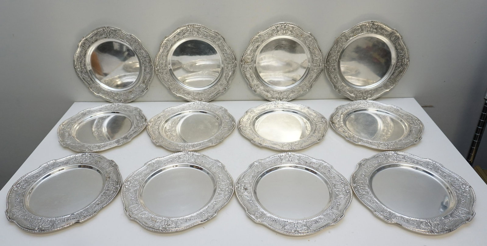 12 E.G. WEBSTER REPOUSSE DINNER SERVICE PLATES: 12 Silver Plated Repousse Dinner Service Plates, first quarter 20th century, by E. G. Webster & Son, Brooklyn, New York, in the continental taste. Each of circular form quartered by serpentine lobes s