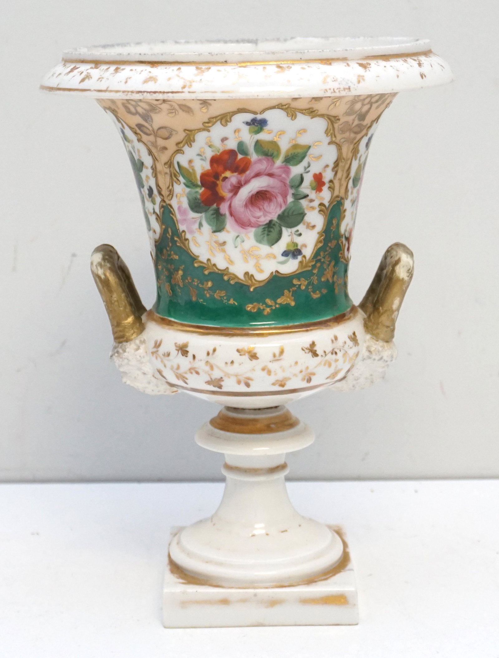 ANTIQUE OLD PARIS URN BACCHUS MASK: Antique Old Paris Porcelain Urn. Hand Painted Floral with Baccus Mask Handles. Wear to gilt, Measures 8"x8"x10 3/4". Weight 4 pds. PROVENANCE: The Estate of Dr. Fraser Wilson, Charleston SC. Dr. Wilso