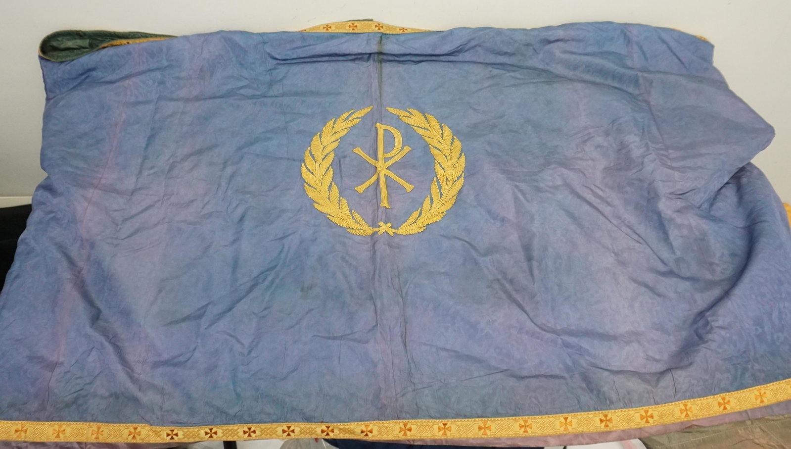 CHRISTIAN ALTAR LITURGICAL FRONT: Early 20th c. Altar frontal liturgical textile, gold-tone brocade embroidery on blue brocade fabric, lined, depicting the Christian chi-rho in the center. Made by the House of Hansen Chicago. Measures