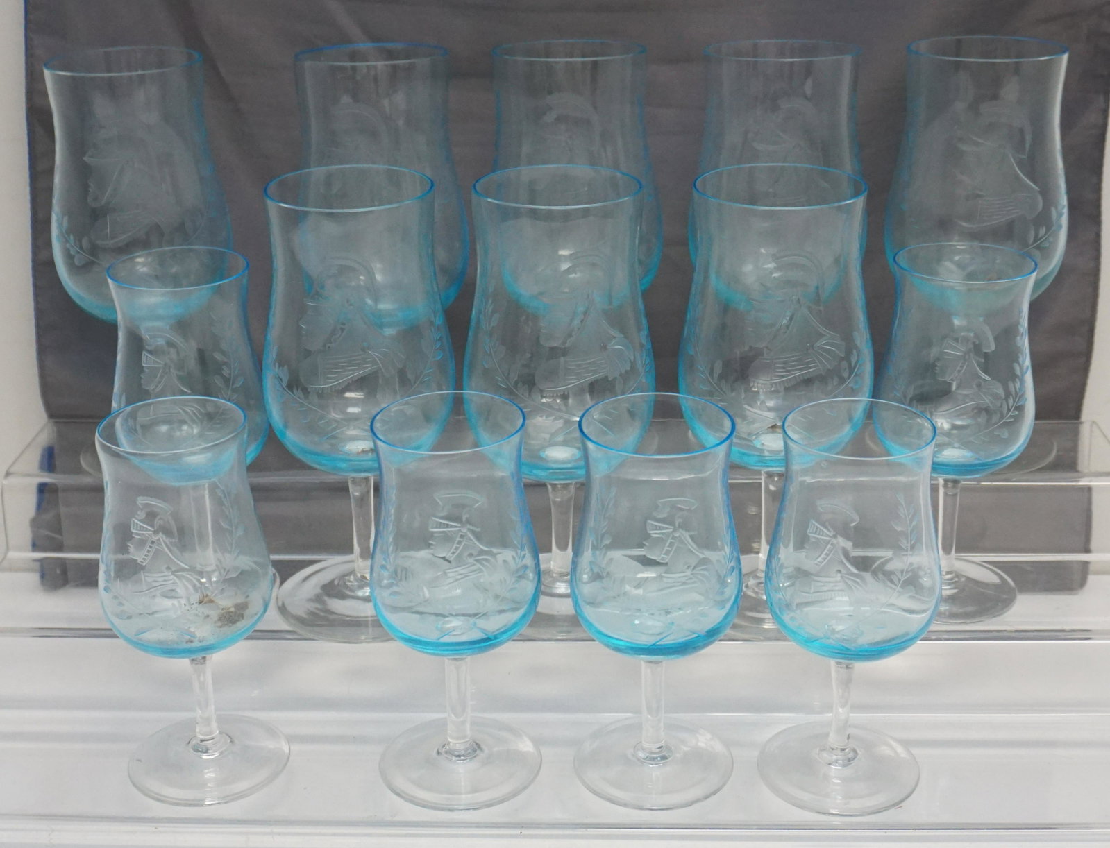 14 VINTAGE MID CENTURY ETCHED BLUE GLASSES: Fourteen Mid Century Etched Glasses. 6 Sherry 5 1/4" and 8 Wine 6 1/2". All with etched Laurel Leaves and Roman Gladiator. Weight on all 4 pds 5 oz. PROVENANCE: A Private Charleston SC Estate.