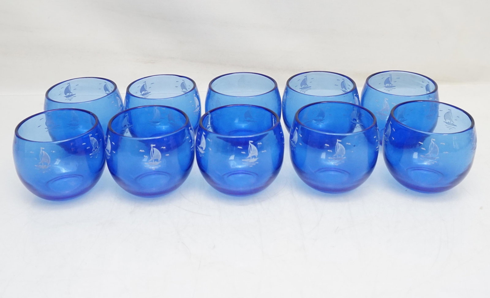 10 HAZEL ATLAS BLUE ROLY POLY GLASSES: Ten Vintage 1950 Mid Century Hazel Atlas Co. Cobalt Blue Sailboat Roly Poly Cocktail Glasses. Great retro look for any bar or bar cart. Each 2 3/8". All in good condition, 1 with fading to boats. Weig