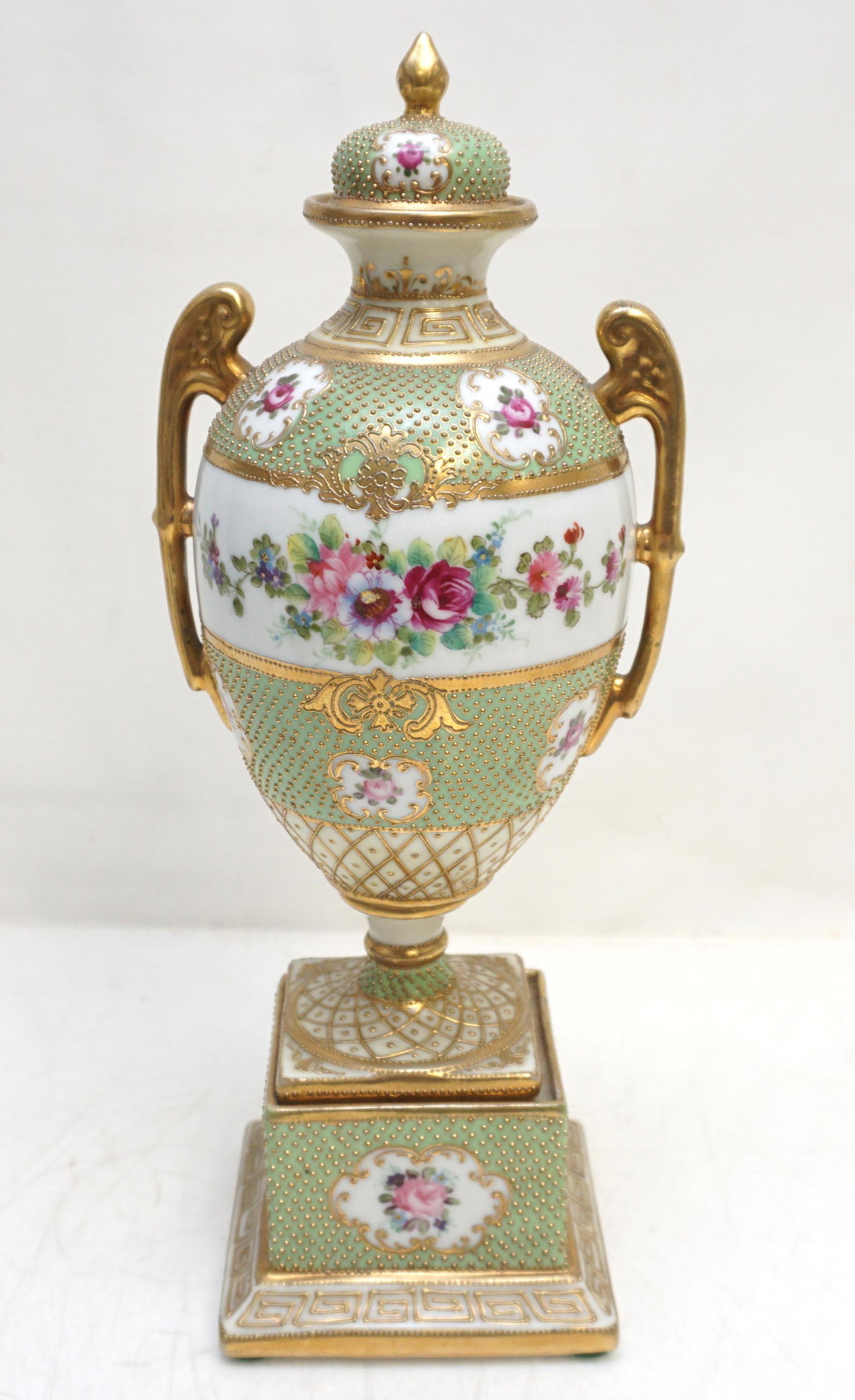 NORITAKE NEOCLASSICAL URN: Early 20th century, Noritake hand-painted floral design, gilt enameling, neoclassical handled lidded urn, pedestal base. Blue Komaru Mark c. 1908. Very good condition. Measures 12". Weight 1 pd 12 oz.