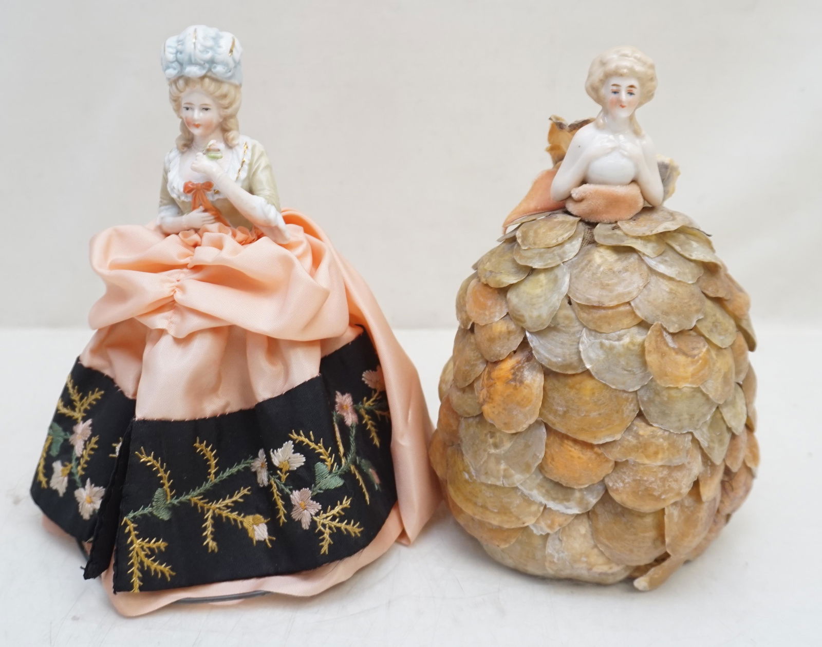 2 GERMAN PORCELAIN HALF DOLL LAMP SHADES: Two Vintage German Porcelain Elegant Half Doll Lamp Shades c. 1920-30. One with a capiz shell skirt. The other with peach taffeta skirt with floral embroidered hem. 7 1/4" and 7 1/2". Weight 9 oz. PRO
