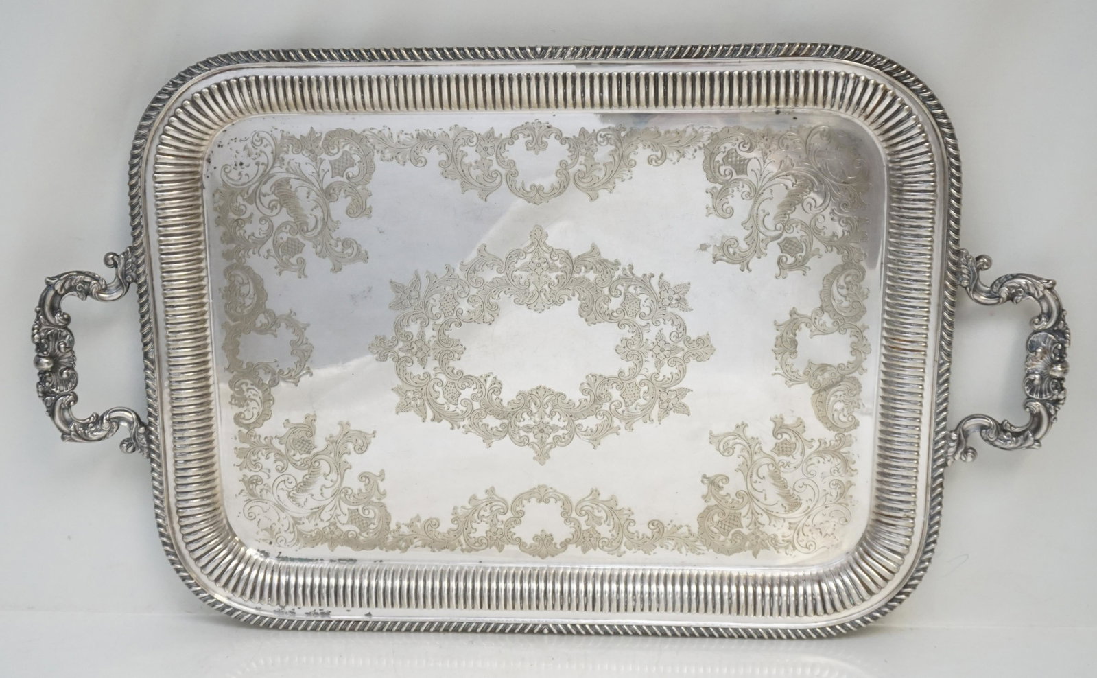 BARKER BROTHERS ENGLISH SILVERPLATE SERVING TRAY: A large rectangular English Edwardian silver plated butlers serving tray with two ornate shell and scroll handles at either end. Tray decorated with floral and scrolling motifs. No monograms. The reve
