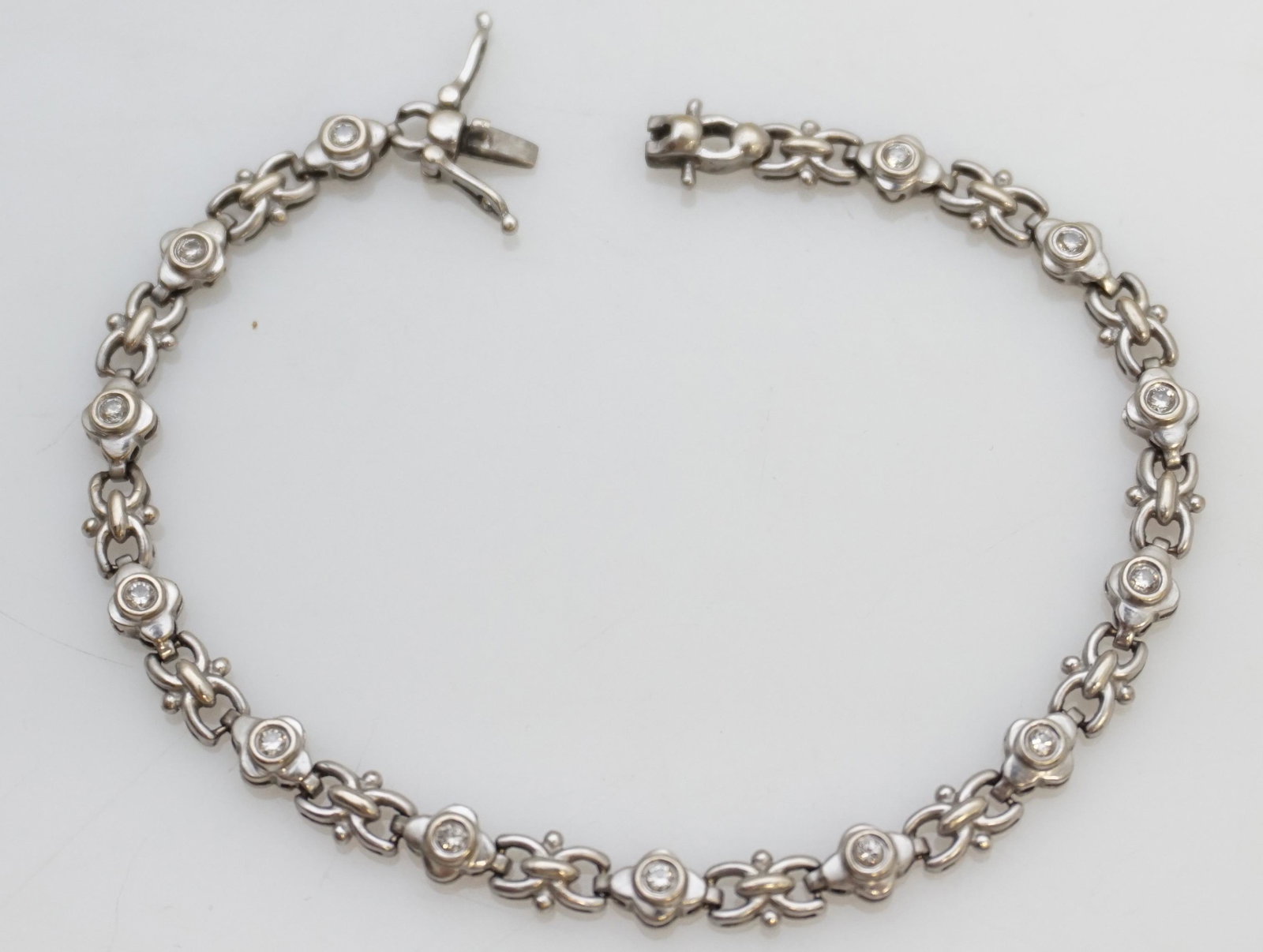 DIAMOND TENNIS BRACELET (7.50 GRAMS): One 14kt white gold diamond tennis bracelet. The bracelet features thirteen (13), bezel set, round brilliant cut diamonds set in a link design. The bracelet is approx. 7.25" in length, 4.95mm wide, ha