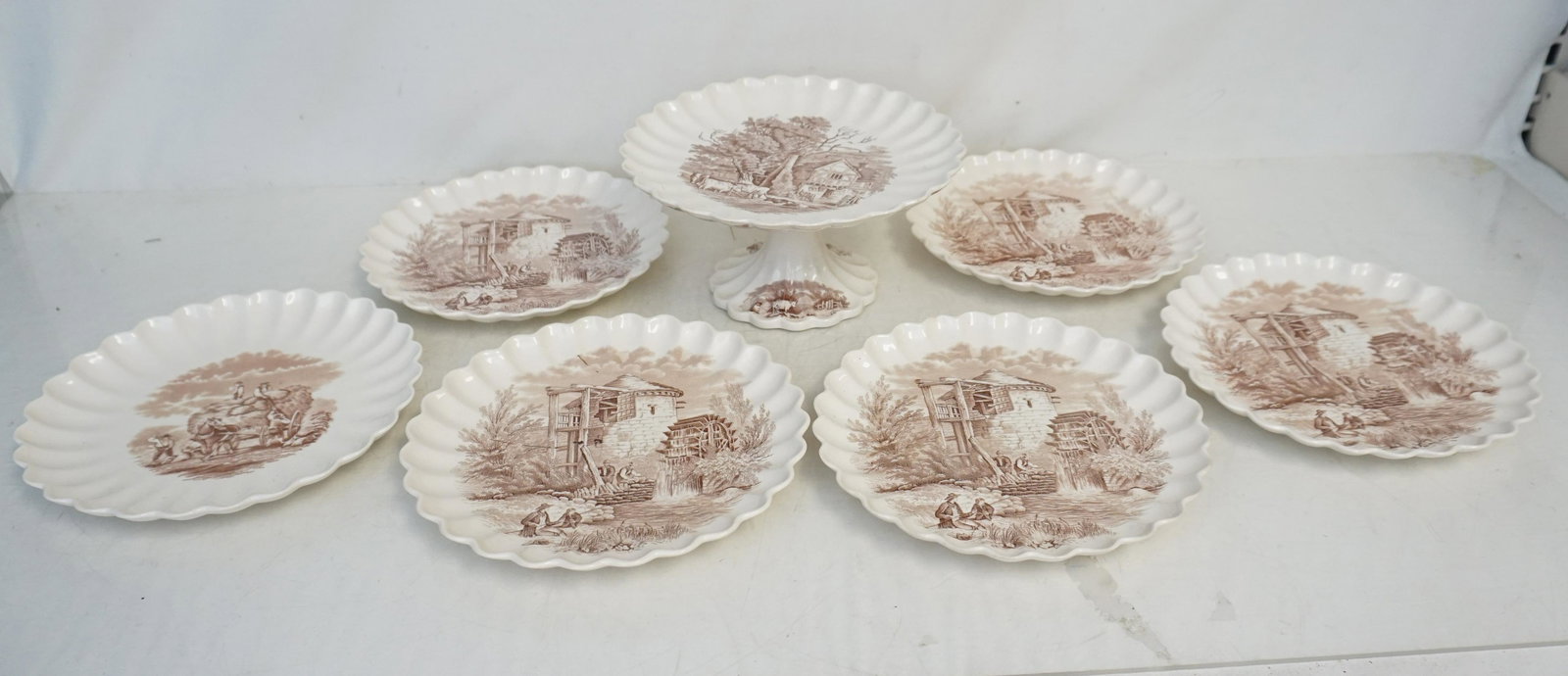 COPELAND SPODE DESSERT SET: Copeland Spode Transferware Pedestal Cake Plate and 6 Dessert Plates. Farm scene for cake plate, 5 old mill plates and 1 farm. Cake plate 8 1/2"x8 1/2"x4". Plates 8 1/2"x8 1/2". Weight on all 4 pds 10
