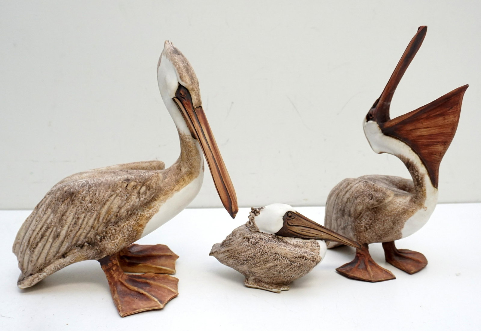3 BRIAN ARTHUR PELICAN SCULPTURES.: Trio of Brian Arthur Pelican Sculptures, all signed on the bottom of their webbed feet. Largest 10" tall and 10" long. Open Beak 10" tall and 7 long, repair to top bill. The Smallest 3 1/3"tall x6" lo