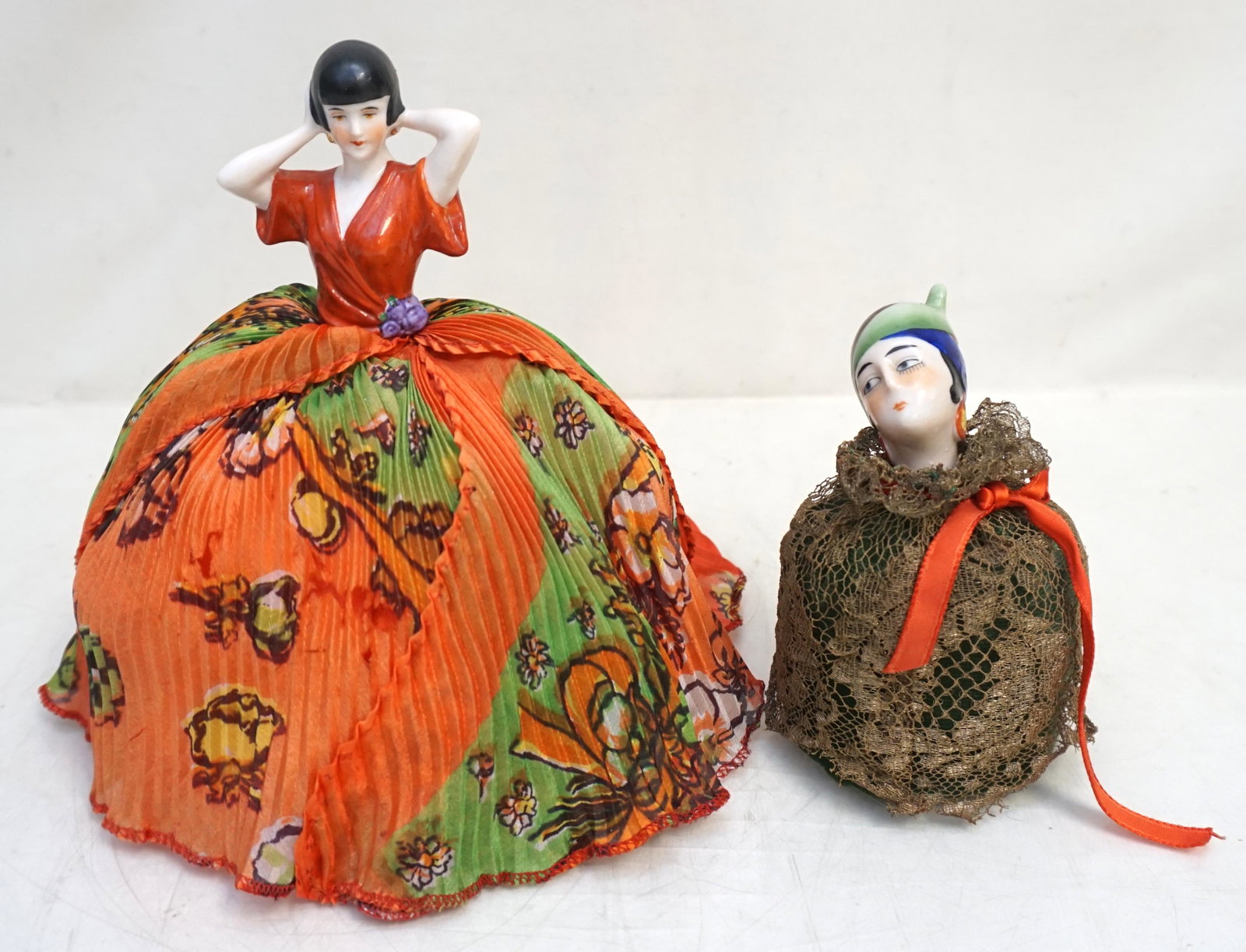 2 ART DECO GERMAN PORCELAIN PIN CUSHION: Two Art Deco German Porcelain Pin Cushions. Larger in Red and Green 5"x5"x7 3/4". Smaller in Hat with lace 2 3/4"x2 3/4"x4 3/4". Weight 9 oz. PROVENANCE: A Private Charleston SC Estate.