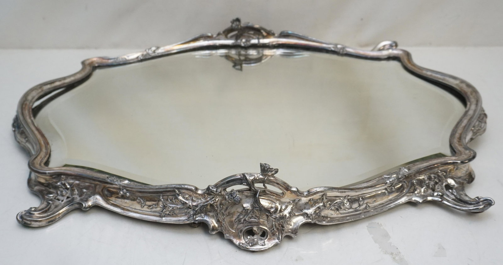 LARGE ART NOUVEAU CONTINENTAL MIRRORED PLATEAU: Large Art Nouveau Period Serpentine Mirrored Plateau. Framed by a heavy Scrolled Rim with Scroll Feet. Original mirrored edge is beveled. Old repair to feet,back is loose, 1 screw missing. No visible 