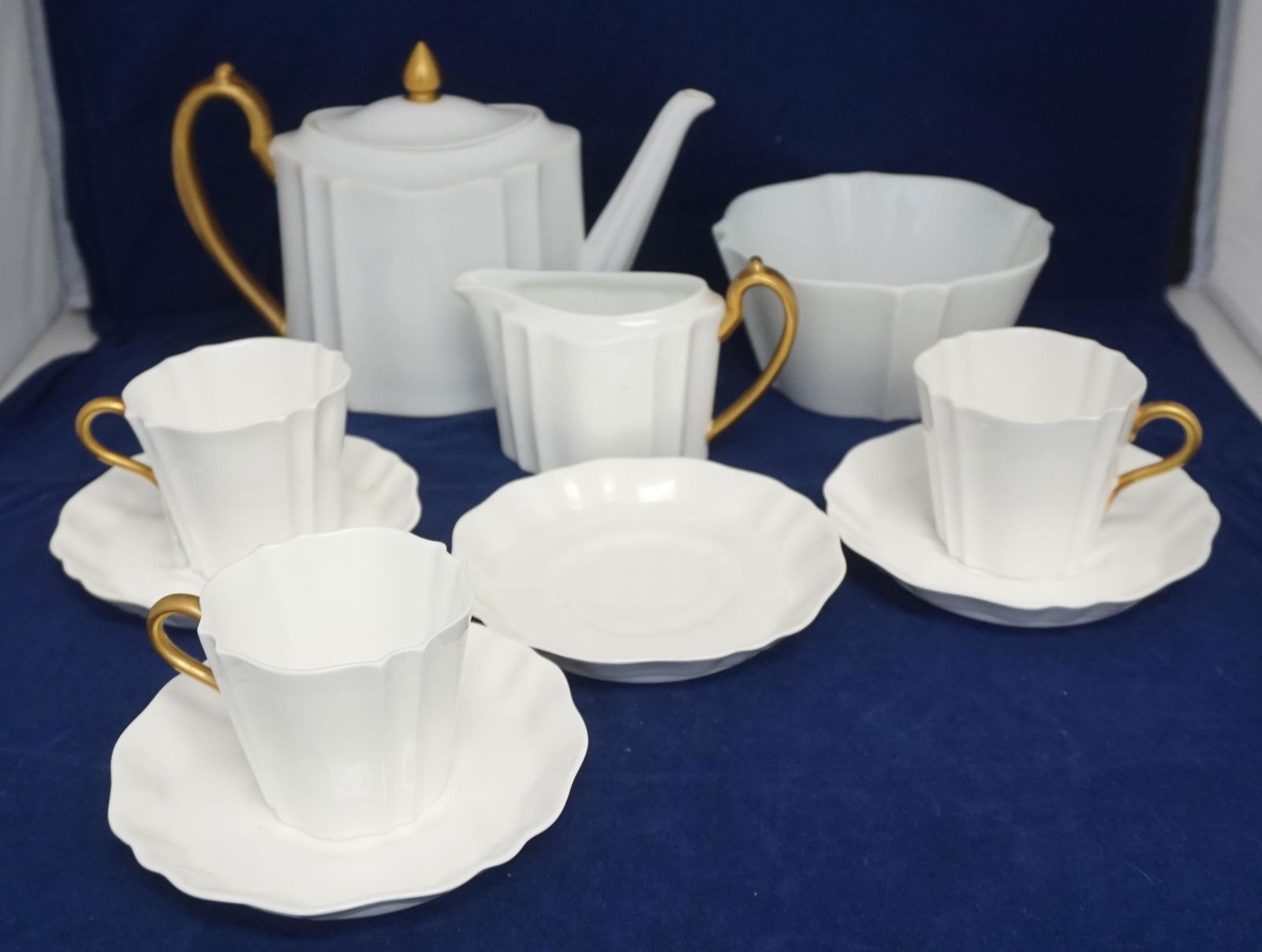 10 pc WEDGEWOOD TEA SERVICE: 10 Pc Vintage Wedgwood England Tea Set. Cream Fluted Porcelain with Gilt accents. Teapot 8" long, Waste Bowl 5"x5"x2 1/2". Creamer 5" long, 4 saucers and 3 cups. Weight on all 3 pds 6 oz. PROVENANCE: