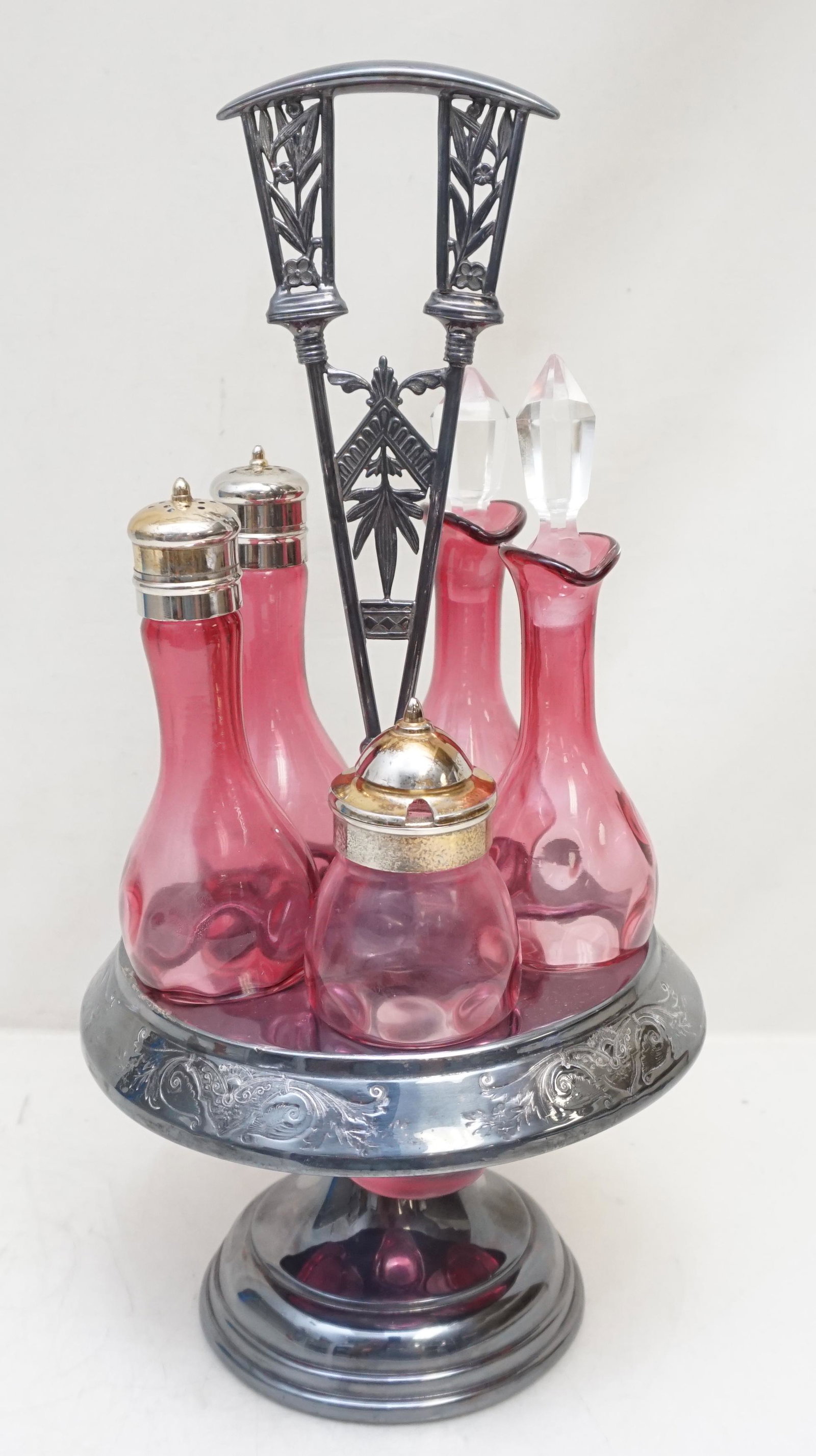 INVERTED THUMBPRINT 5 PIECE CONDIMENT SET: Antique Victorian era 5 Piece inverted thumbprint cased cranberry condiment set, comprising a salt and pepper shaker, a mustard pot and two cruets. Fitted in a Aesthetic Period Silver Plated Stand. Fo
