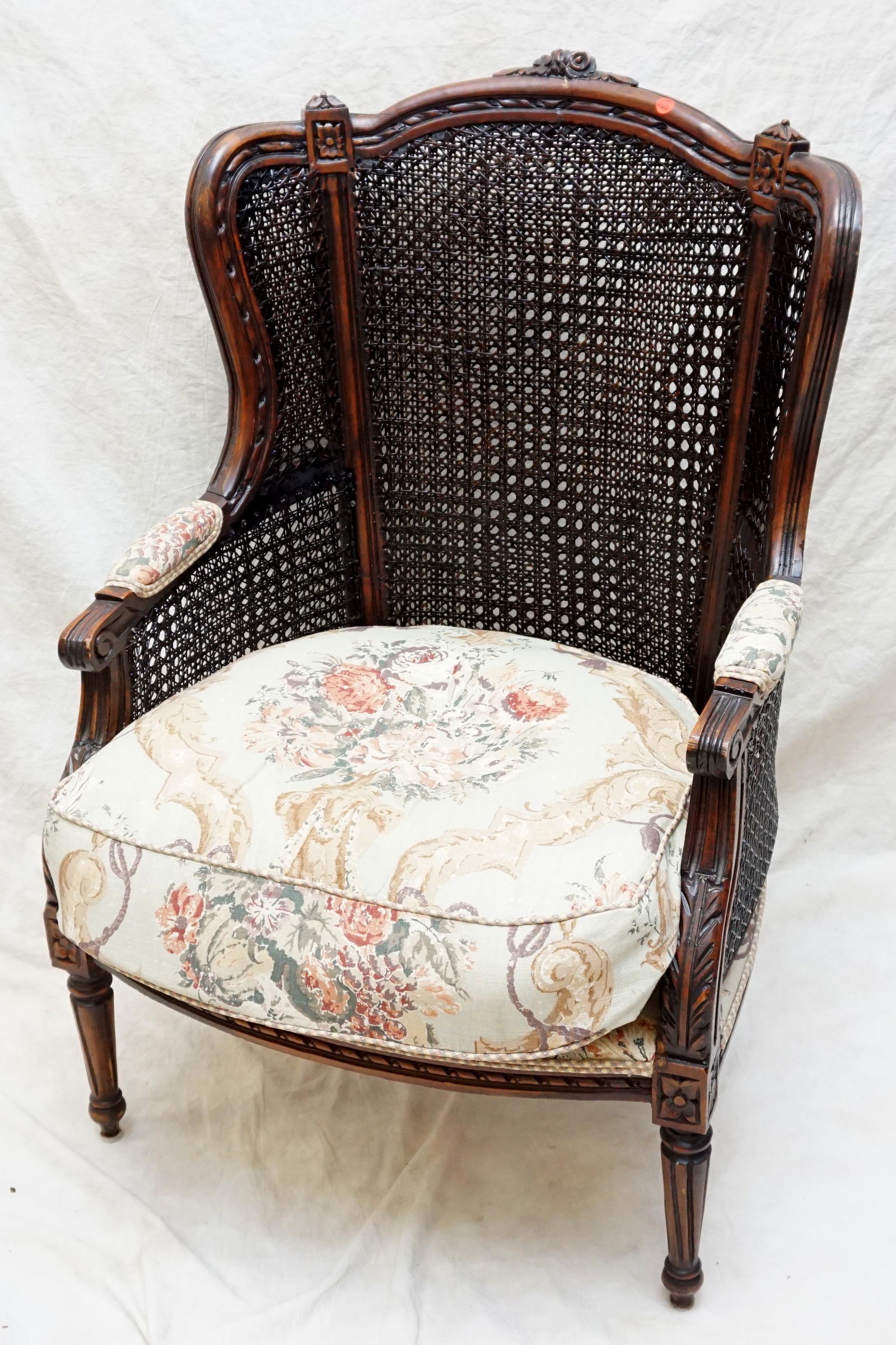 ANTIQUE CARVED CANED BERGERE CHAIR: Antique Carved Walnut French Bergere Chair. Double cane back and sides, Later upholstered seat. Measures 27"x28"x42". PROVENANCE: A Private Charleston SC Estate. ***Pickup only or Shipping on this ite