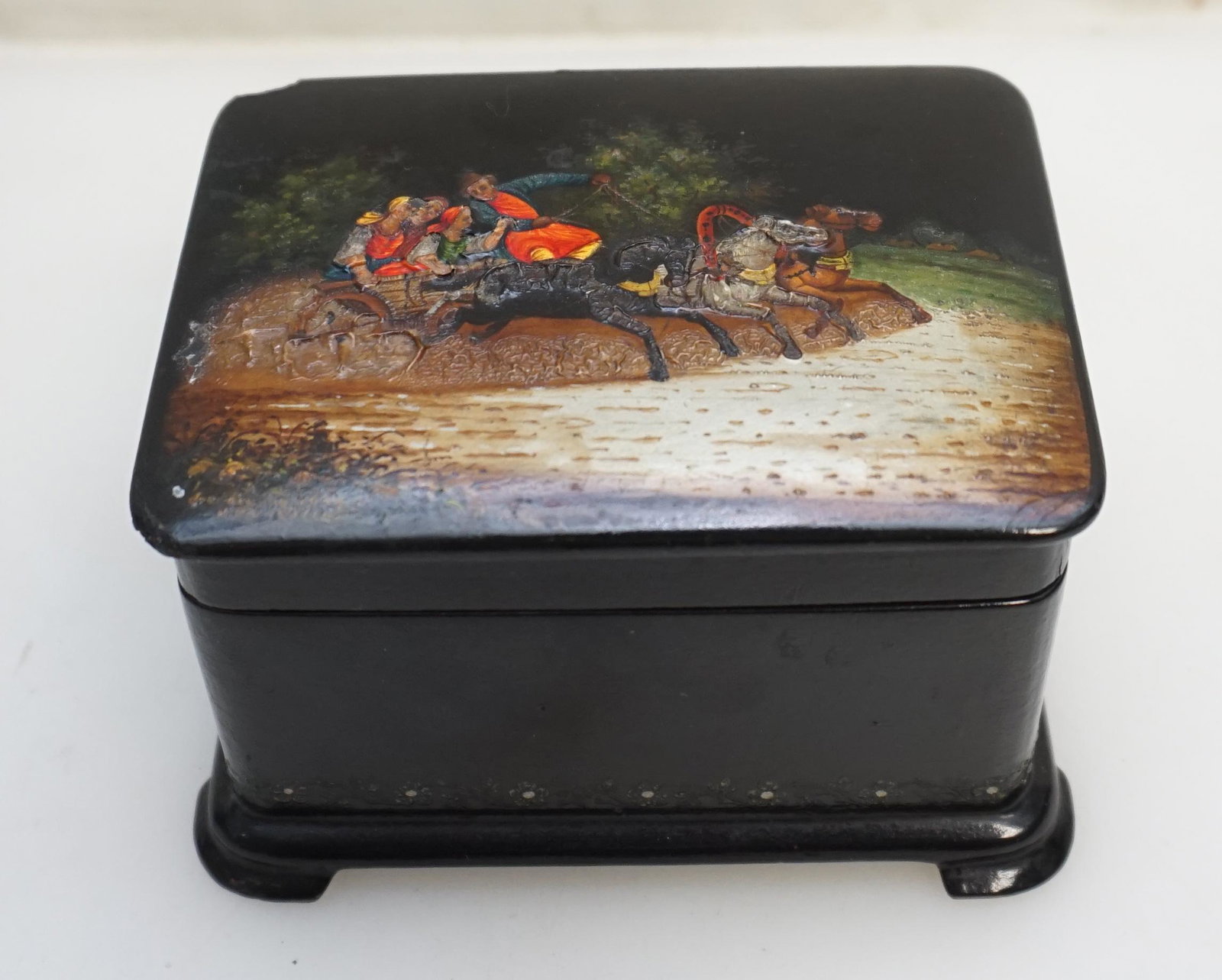 RUSSIAN LACQUER BOX DEPICTING TROIKA: Vintage 1954 Russian Lacquer Cigarette Box. Papier Mache with layers of black lacquer and a hand painted Troika. Signed and dated 1954. Chip to one corner, age appropriate wear. Measures 4"x3"x2 1/2".