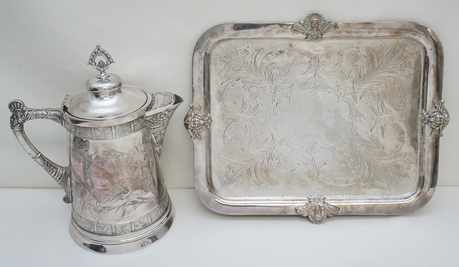 2 PC AESTHETIC SILVERPLATE TRAY + WATER KETTLE: Both are Antique American Silverplate. Both monogrammed. 1- American Aesthetic Wilcox Silverplate Tray Swith figural head decoration 17 1/2"x14". 2- Large Aesthetic Water Kettle, no stand. 10 1/2"x7 1