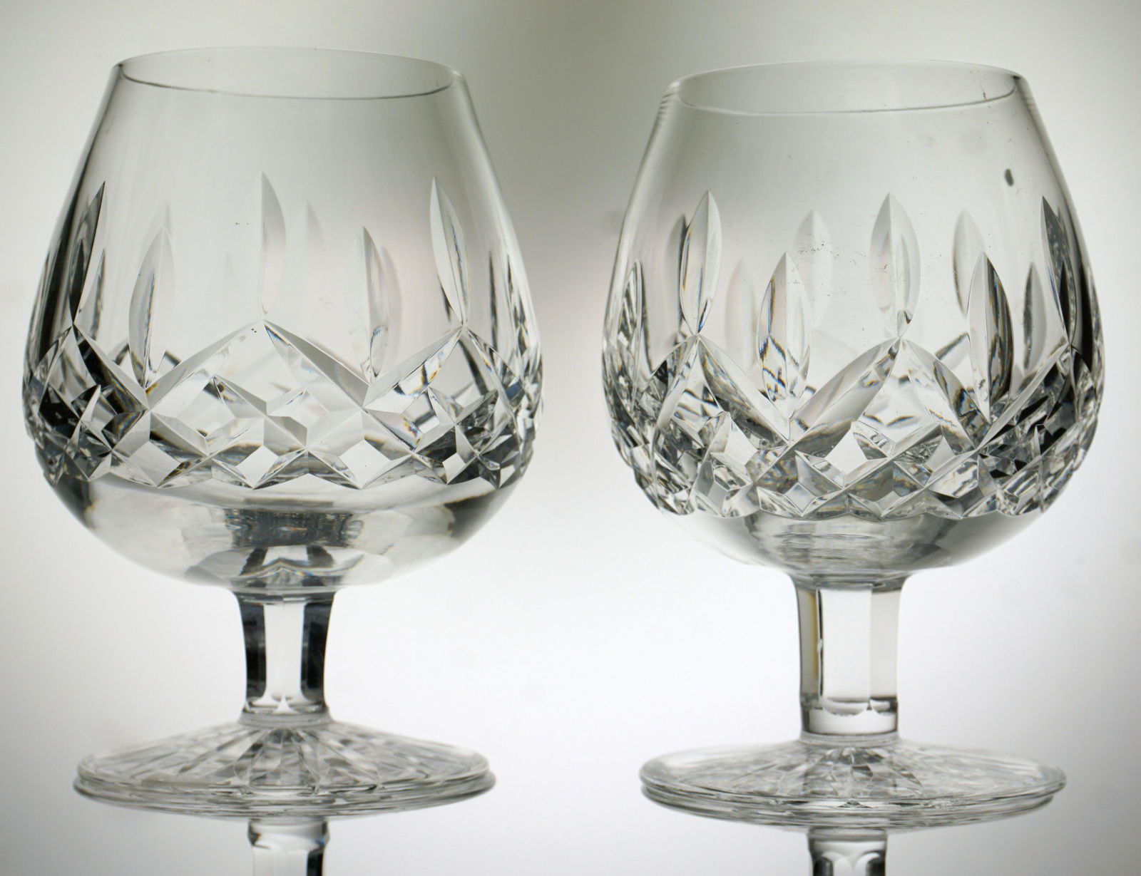 4 WATERFORD CRYSTAL LISMORE BRANDY: Four (4) Waterford Lismore Brandy Snifters. All with a series of staggered wedge-cuts with a band of cross hatch cuts below to the bowl on a cut foot. Acid etched maker's mark. Each measures 5 1/4" ta