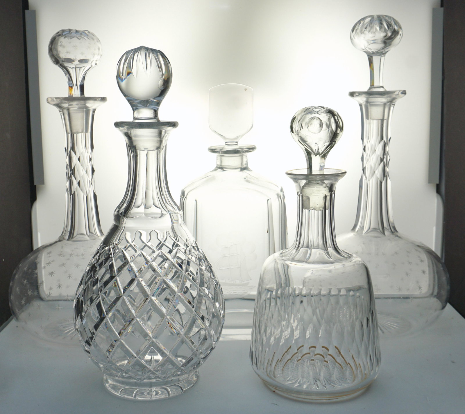 5 VINTAGE CRYSTAL DECANTERS: 1- Orrefors Crystal Decanter with Etched Ship Designed by Nils Landberg 9 1/2". 2&3- A pair of Mid Century tall Decanters with etched stars, each 12", both with a chip to rims. 4- Ceska Decanter with 