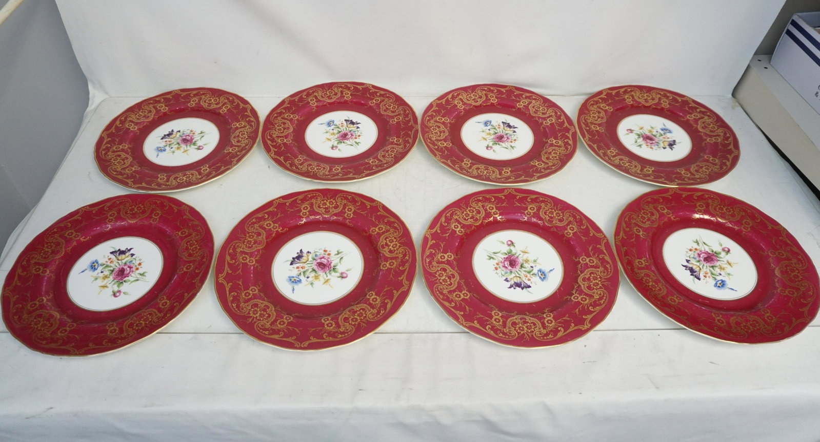 8 ROYAL WORCESTOR DINNER PLATES: 8 1930s Royal Worcester Elegant Red Dinner Plates. Floral Transfer centers with gilt accented rims. Each 10 3/4". Weight 12 pds. Some wear to red. PROVENANCE: A Private Charleston SC Estate.