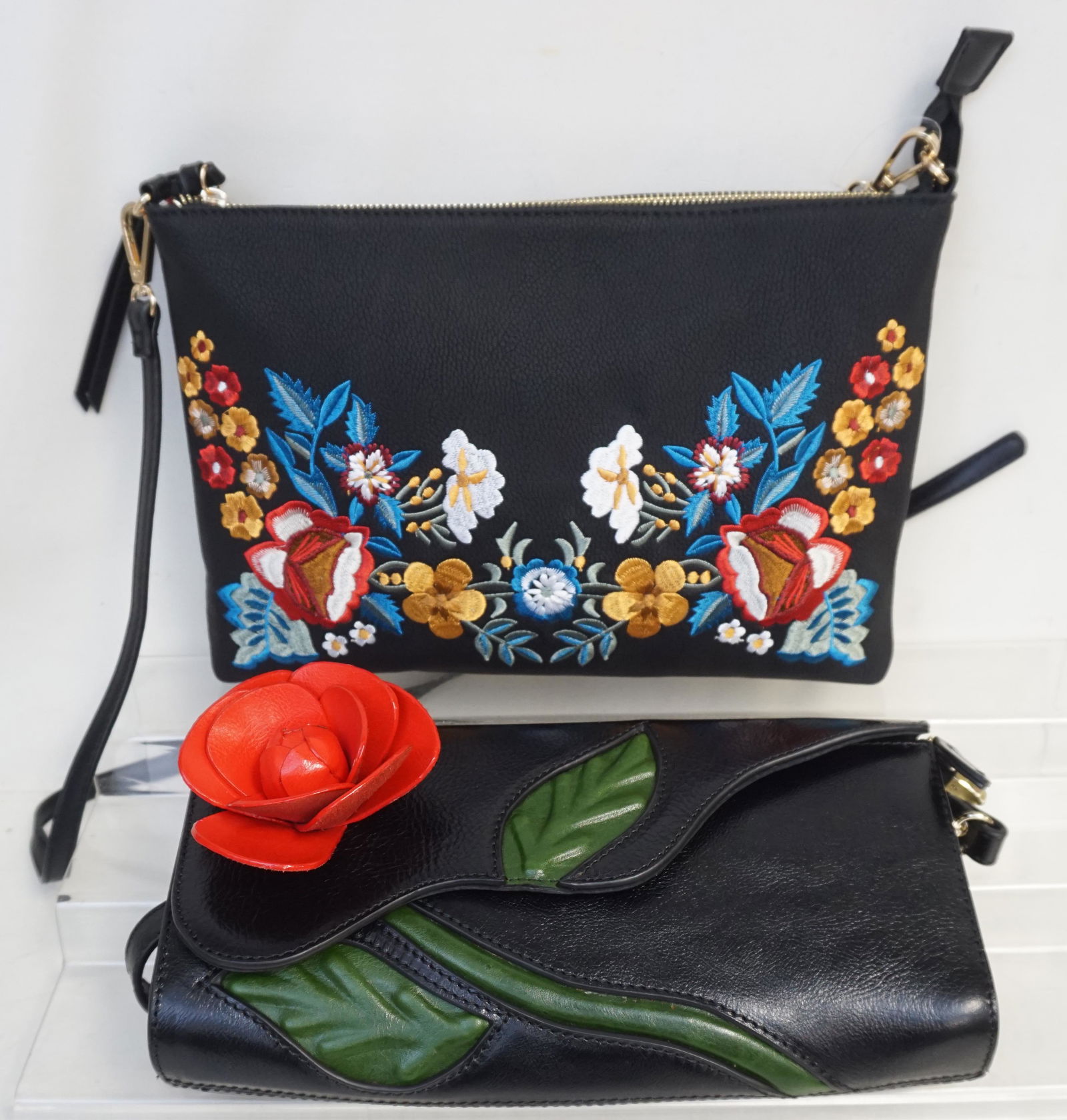 2 EMBELLISHED BLACK SHOULDER BAGS: Both are new and usused. 1- Black Leather Bag with Leather Rose and Vine Accents. With Shoulder strap. Measures 11 1/2" Long. 2- Black Bag with embroidered Floral Accents 12" long. Weight 2 pds 10 oz.