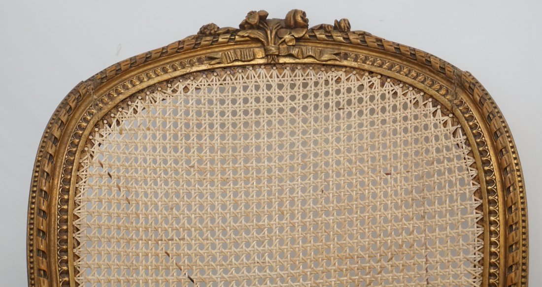ANTIQUE LOUIS XVI STYLE BERGERE CHAIR: Antique late 19th, early 20th c. Louis XVI style bergere in fruit wood and cane with ribbon and floral carved crest rail and continuous arm raised on stop fluted legs. Measures 25"x18"x40".. PROVENANC