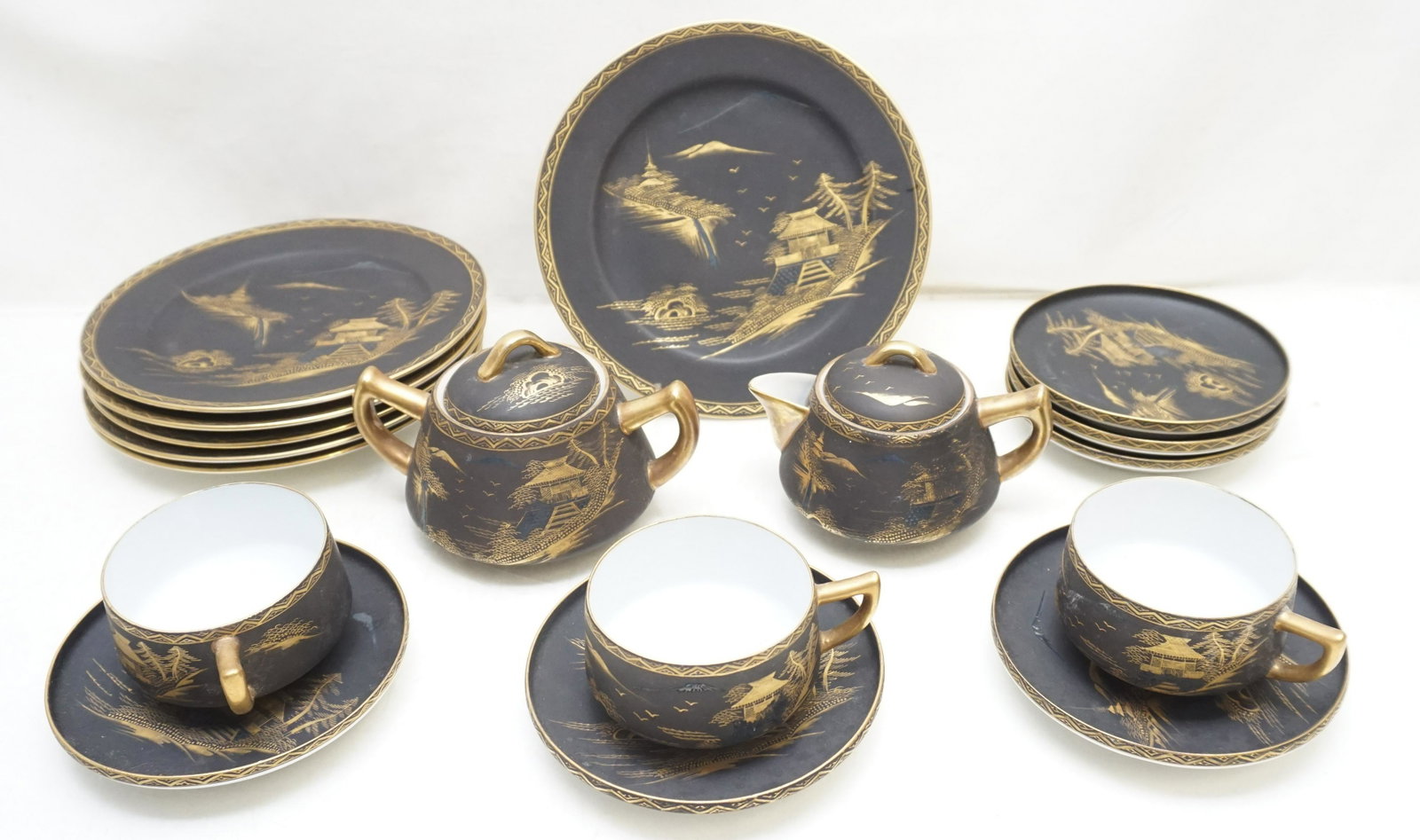 18 PC MID CENTURY KUTANI TEA SET: 18 Piece Kutani Mid Century Black Matte Partial Tea Set. All hand painted in gilt with Mt. Fuji and pagodas. 6 Saucers 5". Cream and Sugar 3 1/2". 3 Teacups 2". 6 Dessert Plates 7 1/2". Weight on all 