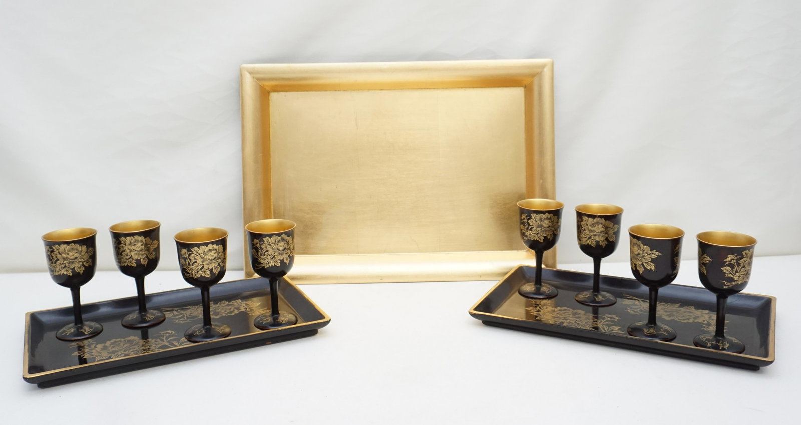 12 PC JAPANESE BLACK LACQUERED COCKTAIL SET: 12 Piece Vintage Japanese Black Lacquer and Gilt Cocktail Set. Set consists of 3 trays. Largest is gold leaf and black 16 1/4"x11 1/2"x1". Two matching Trays 12"x7" and 8 Cordial / Wine glasses 4 1/4"