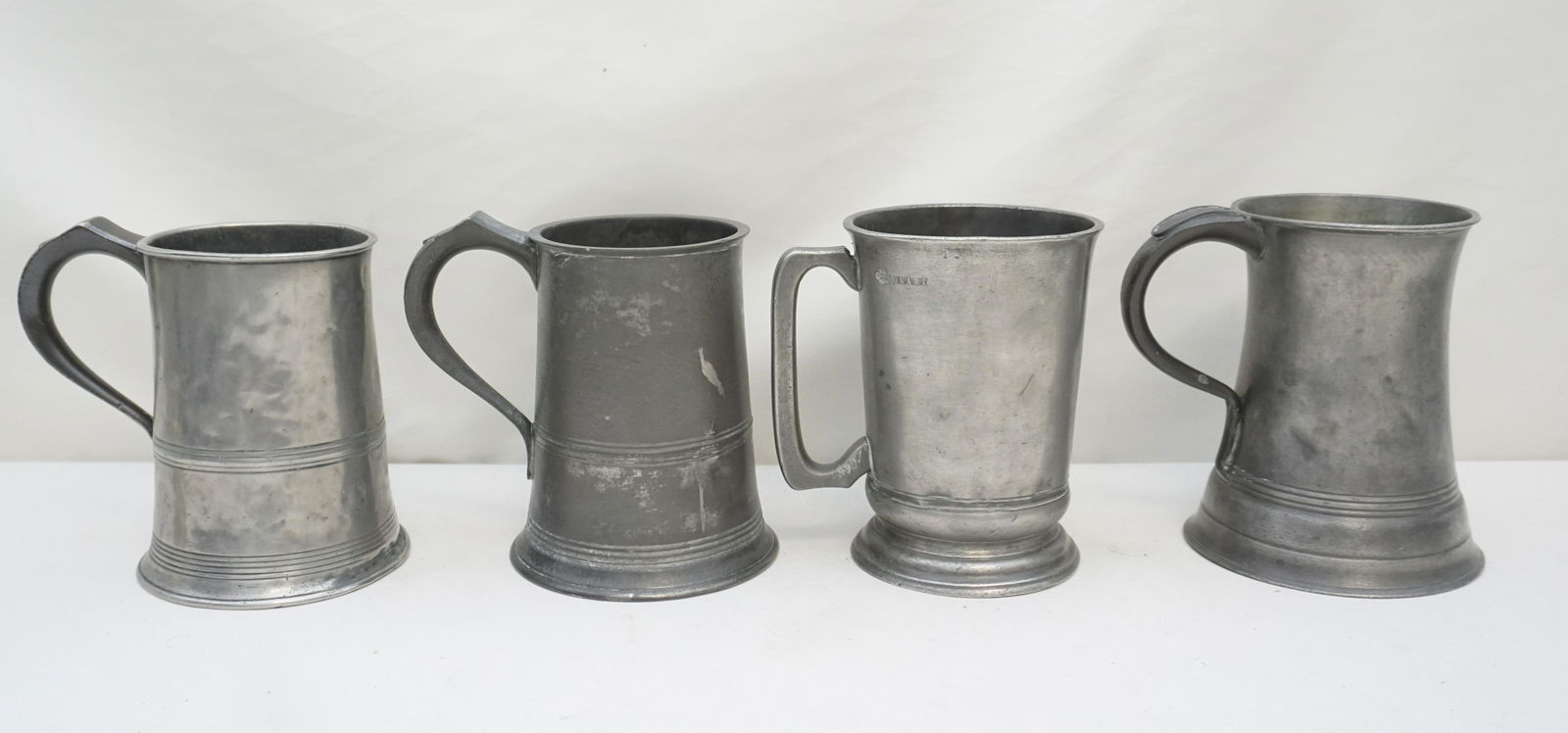 4 ANTIQUE PEWTER QUART MUGS: All are Antique. 1- English Quart Mug c. 1836, 6 1/2" good antique condition. 2- English Quart Mug, monogrammed, by Grimes & Son, London, 6 1/2" some dings. 3- American Quart Mug by T.D. Boardman with
