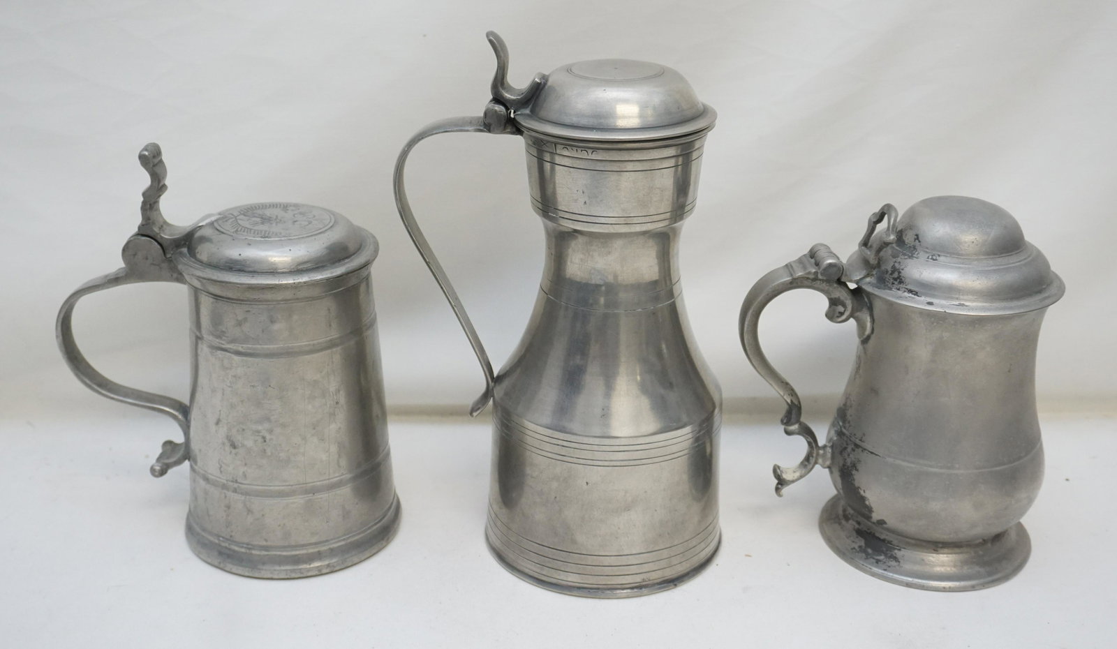 3 ANTIQUE CONTINENTAL PEWTER TANKARDS: All are Antique. 1- A Mid-18th Century English Dome-lidded Pewter Tankard circa 1750, tulip shape having double curved handle and open back thumb piece. 7 1/2".good,minor wear. 2- Australian Quart Pew