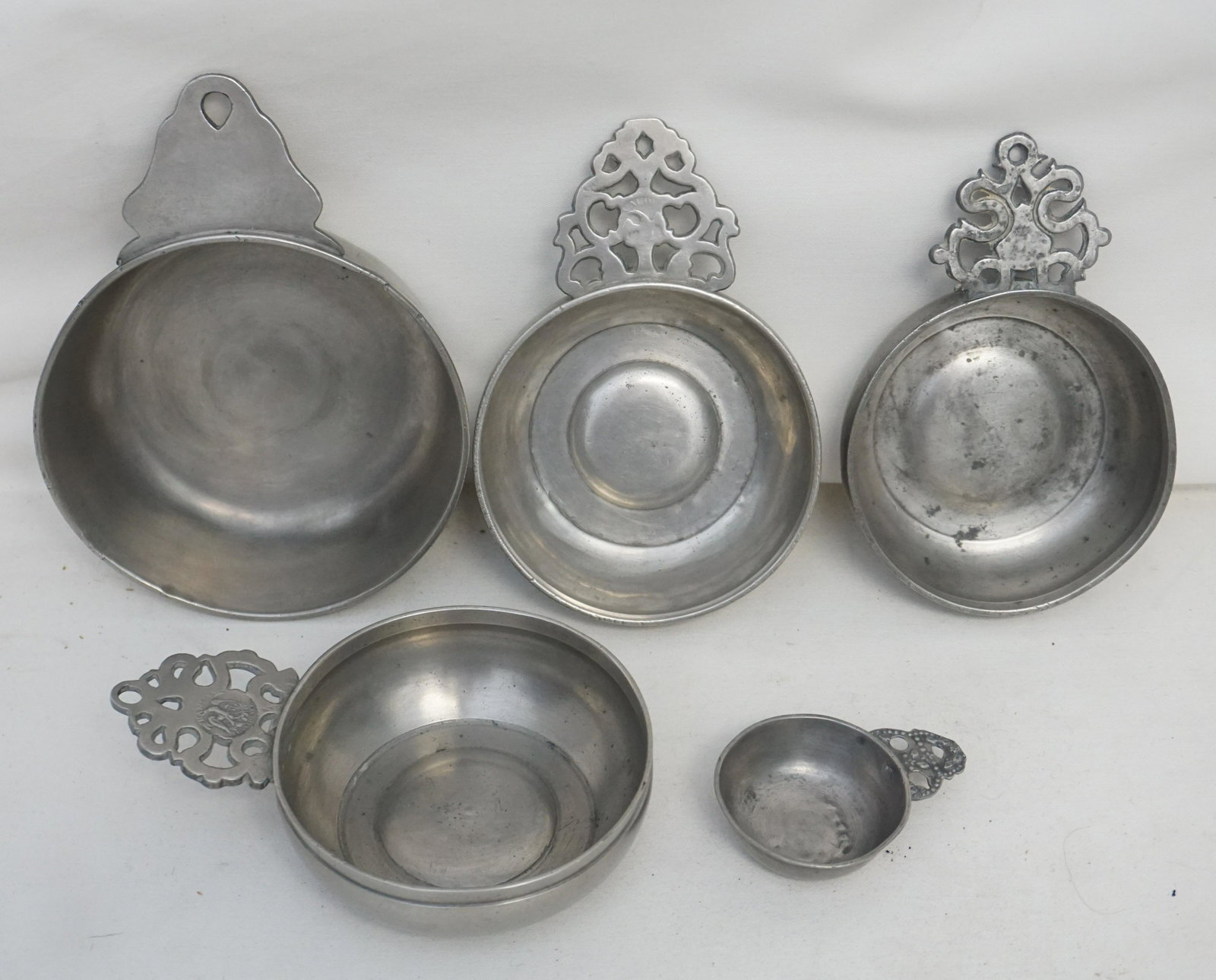 5 18th / 19th c. AMERICAN PEWTER PORRINGERS: All are Antique. 1- Flowered handle porringer marked by Samuel Hamlin Jr. of Providence, Rhode Island. He worked from 1801 to 1856. The bowl is 4 1/8” Good condition. 2- Flowered handle porringe