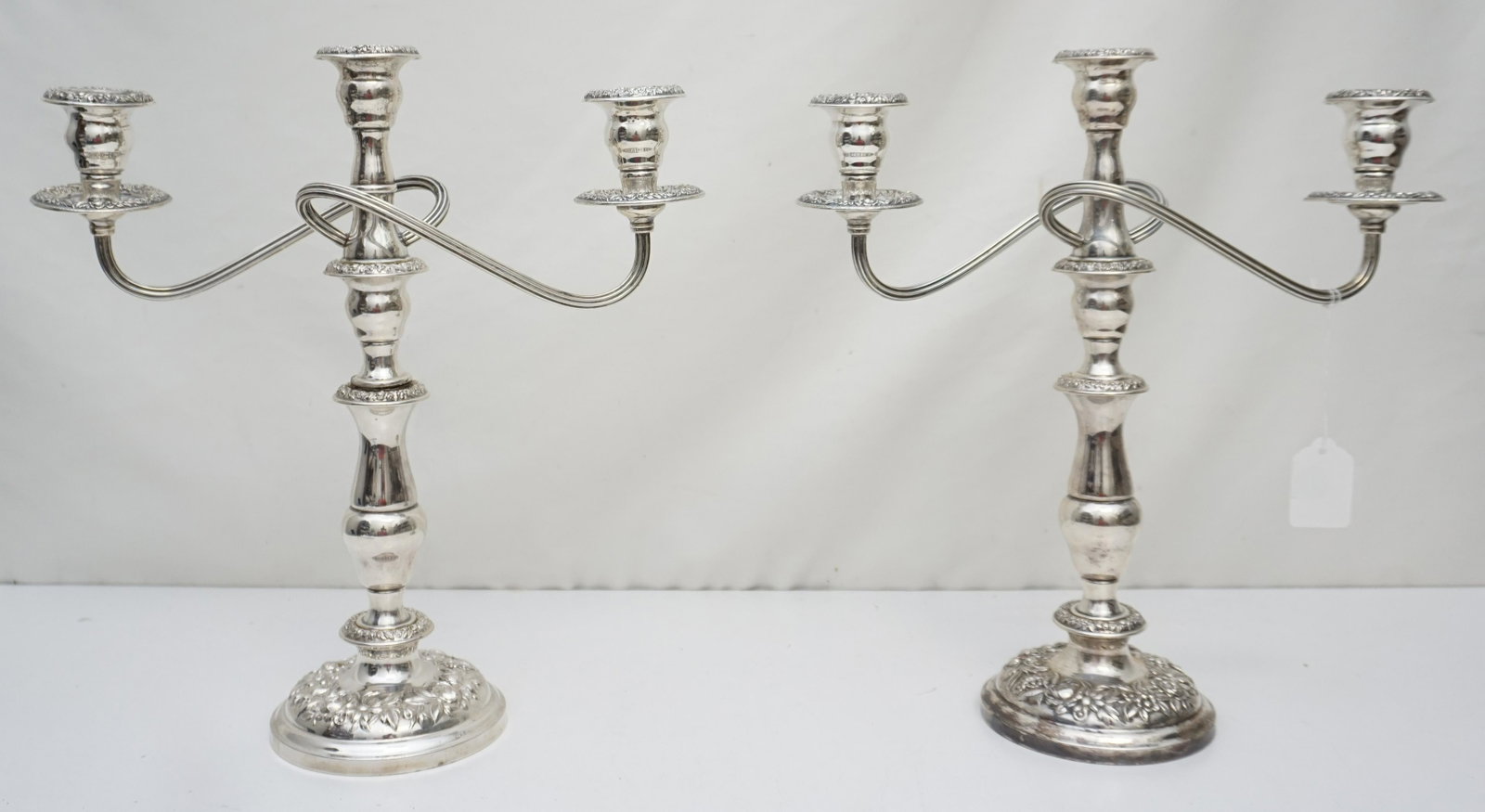 PAIR S. KIRK STERLING SILVER CANDELABRA: Pair of Sterling Silver S. Kirk & Son Candelabras with repousse Floral Design. Weighted. Each measures 13" x 14" inches. One does not come apart as it has been repaired. Weight 7 pds 2 oz. PROVENANCE: