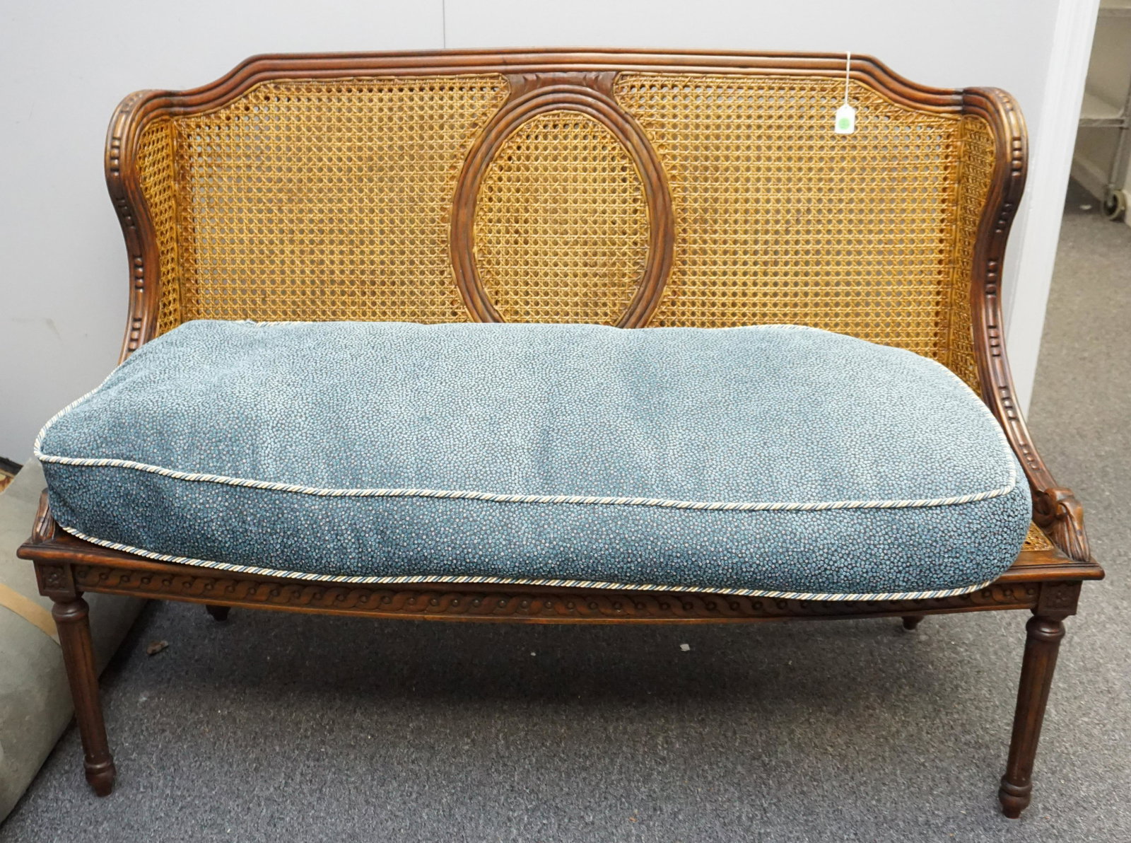 GUILD MASTER CANE BENCH W PILLOW: 20th c. Guild Master design hand-carved old world style bench. Double caned back, down filled cushion covered in a blue Brunschwig & Fils fabric. This versatile bench can be used at the foot of the be
