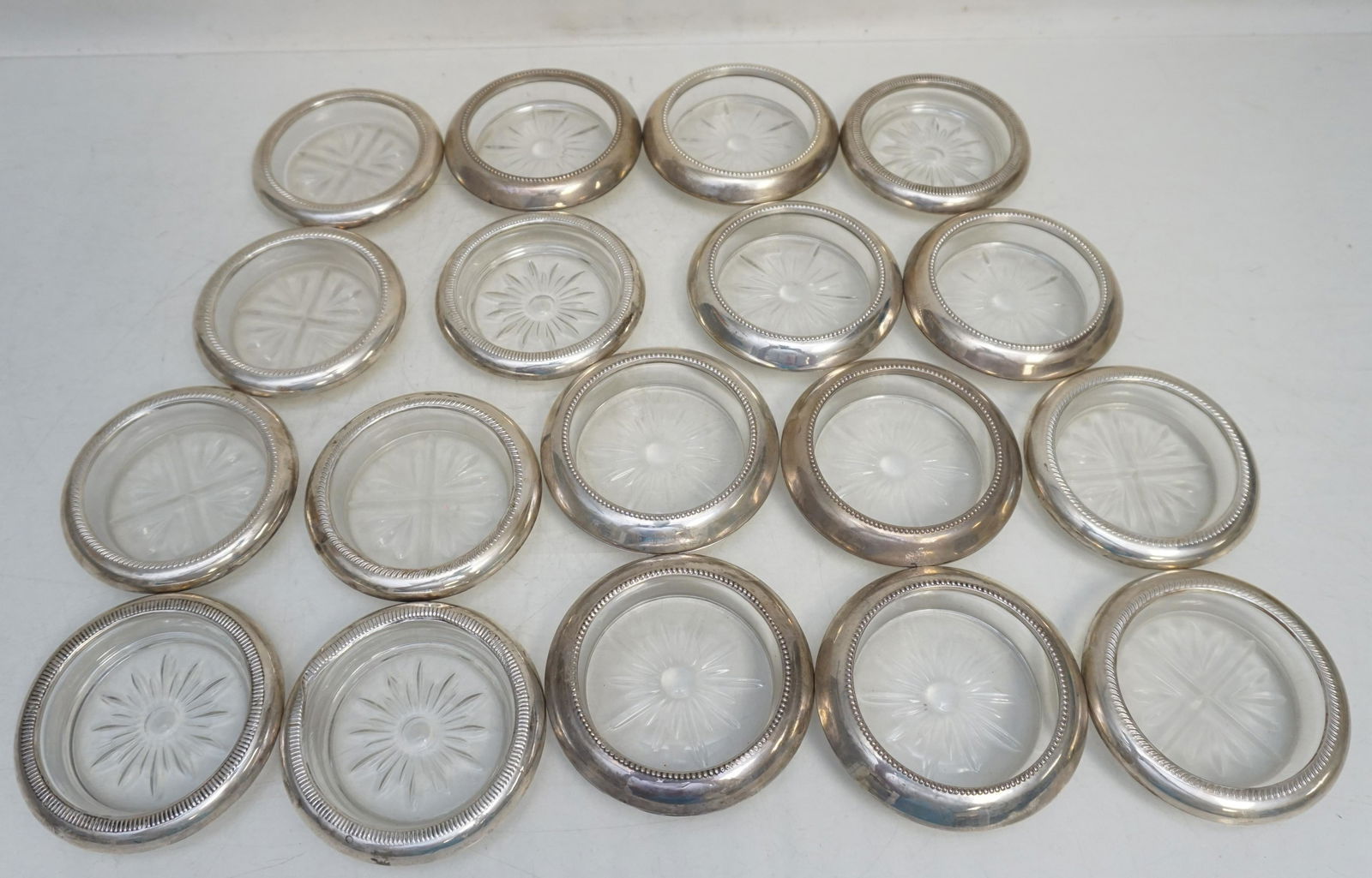 18 STERLING RIMMED COASTERS: All are Vintage Sterling Rimmed and Glass Coasters. 8 by Frank M. Whiting. 4 by Crown (1 dented) and 6 Rogers. Weight on all 6 pds 3 oz. PROVENANCE: Edwin Moore Brogdon, PhD, collection. Dr. Brogdon w