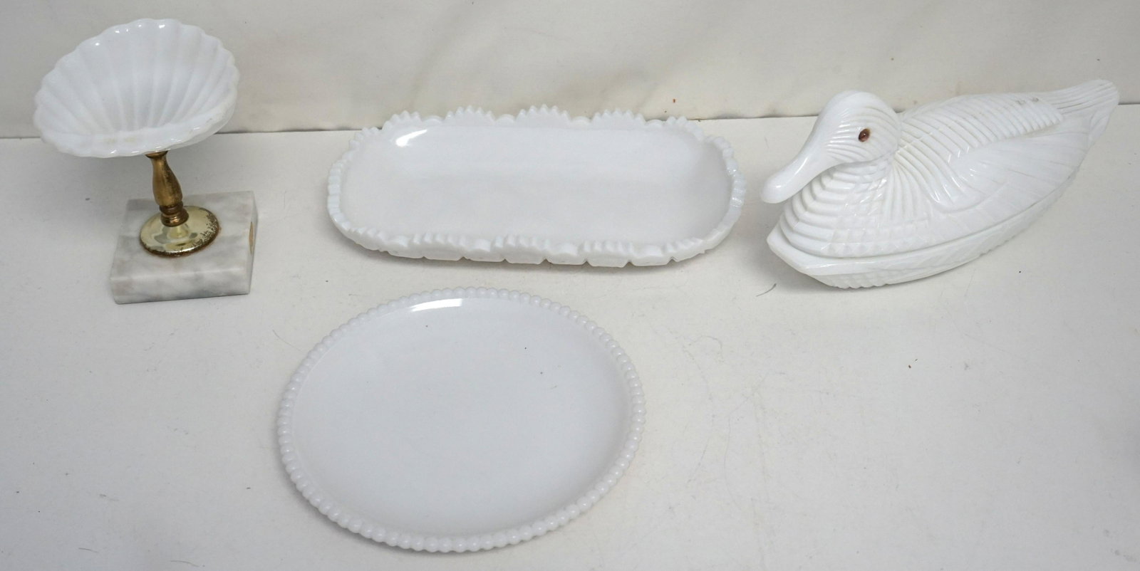 4 PC VINTAGE MILK GLASS DUCK +: 1- L.G. Wright 20th c. Covered Duck Dish with Glass Eyes 11" long. 2- Westmoreland Old Quilt Pattern Pickle / Relish Dish 10" long. 3- Westmoreland Beaded Edge Plate 7 1/2". 4- Vintage Milk Glass Shel