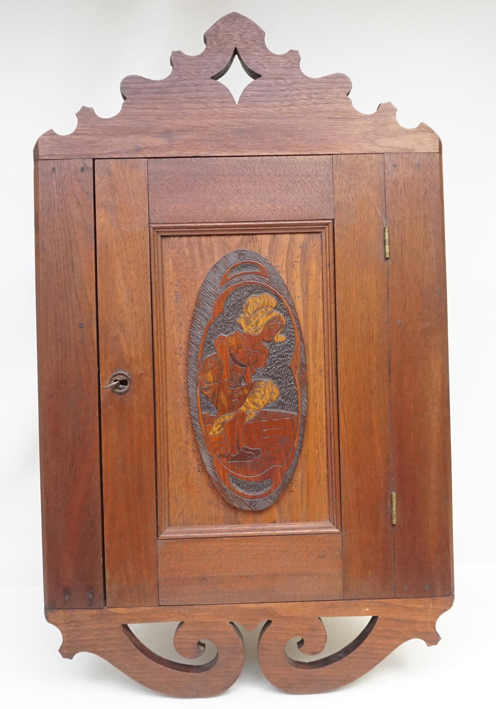 ANTIQUE DUTCH HANGING CORNER CUPBOARD: Antique c. 1910 Dutch Hanging Corner Cupboard with Carved Dutch Girl Plaque. Locking with key. Measures 17"wide x12 1/2" deep x 28" high. Weight 15 pds. PROVENANCE: A Charleston SC Private Estate.